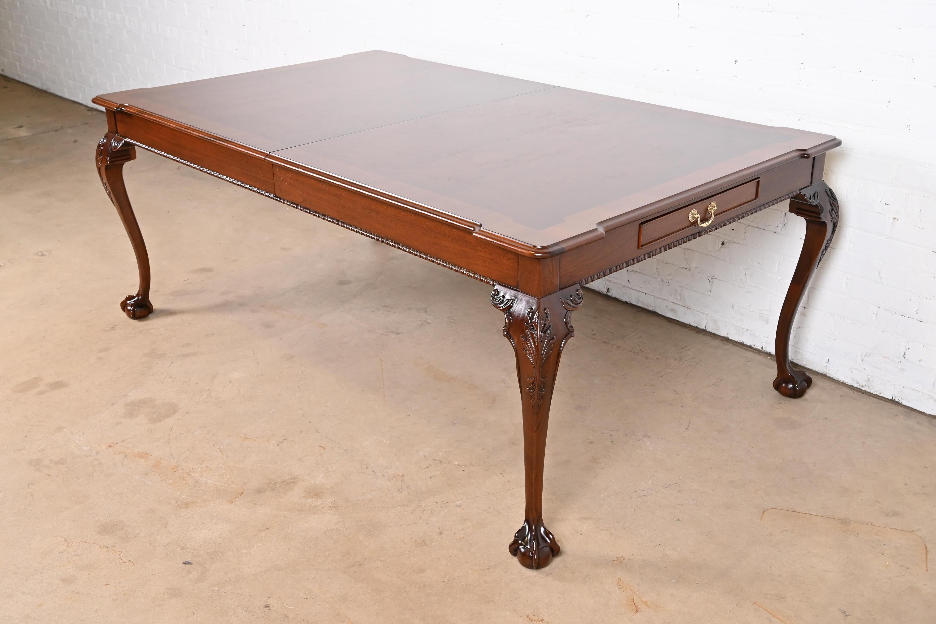 An exceptional Chippendale or Georgian style extension dining table

By Henredon

USA, Circa 1980s

Gorgeous book-matched burled walnut top, with mahogany banding, carved solid mahogany legs with ball and claw feet, and brass hardware on silverware