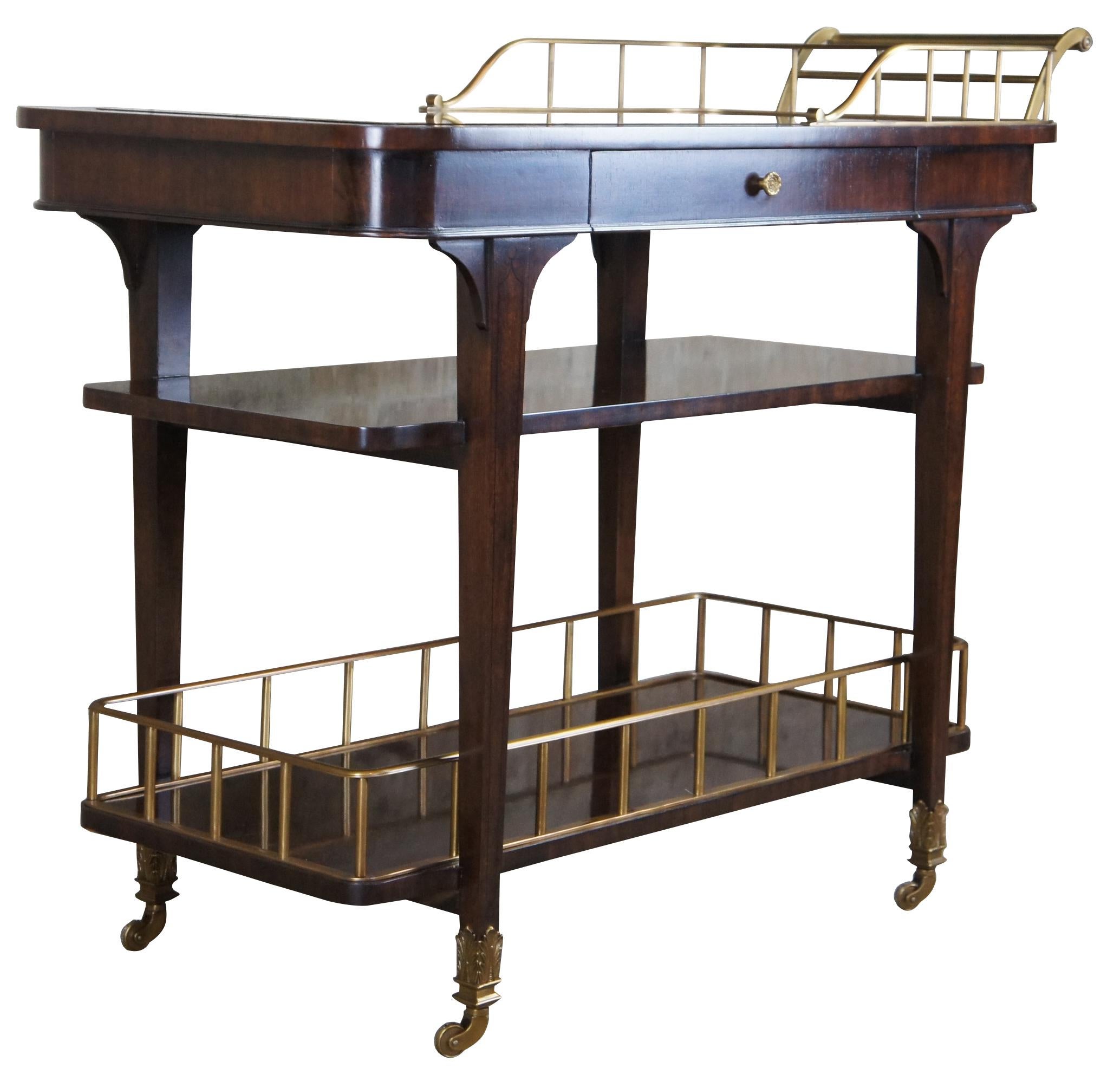 Three tier Henredon Furniture bar cart. Made from premium Mahoni and Gemelina wood, and Walnut veneers; and featuring brass galleries, mirrored top, lined accessories drawer, and swivel castors.

Measures: 43.5