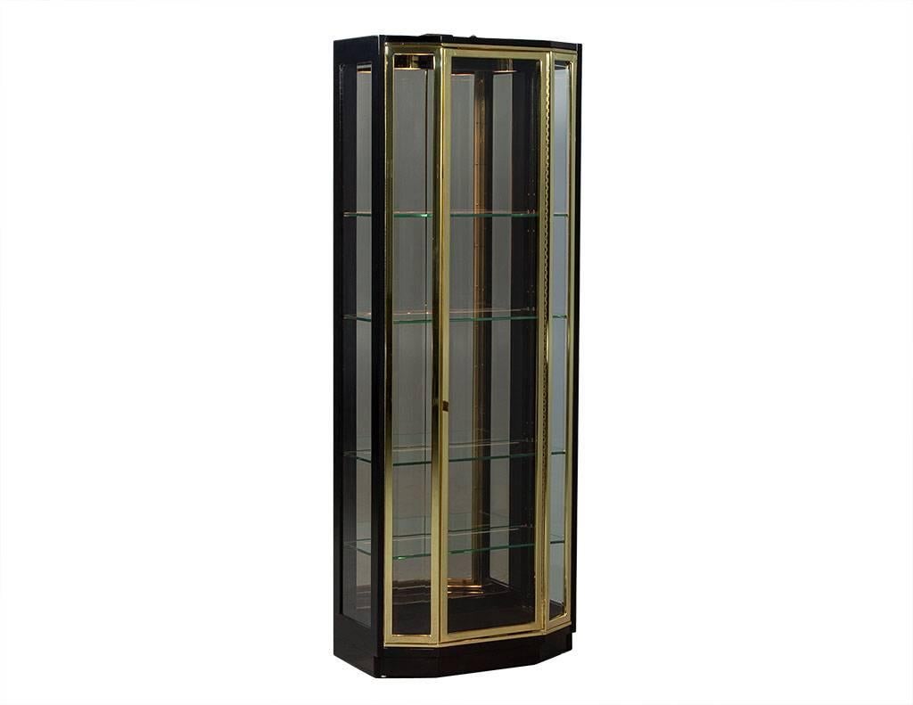 This Mid-Century Modern curio is absolutely lovely. Featuring clean ebonized frame with brass trim on the door, four glass shelves and a mirrored back. The bevelled glass door and sides only add to the charm and beauty of the piece. The perfect