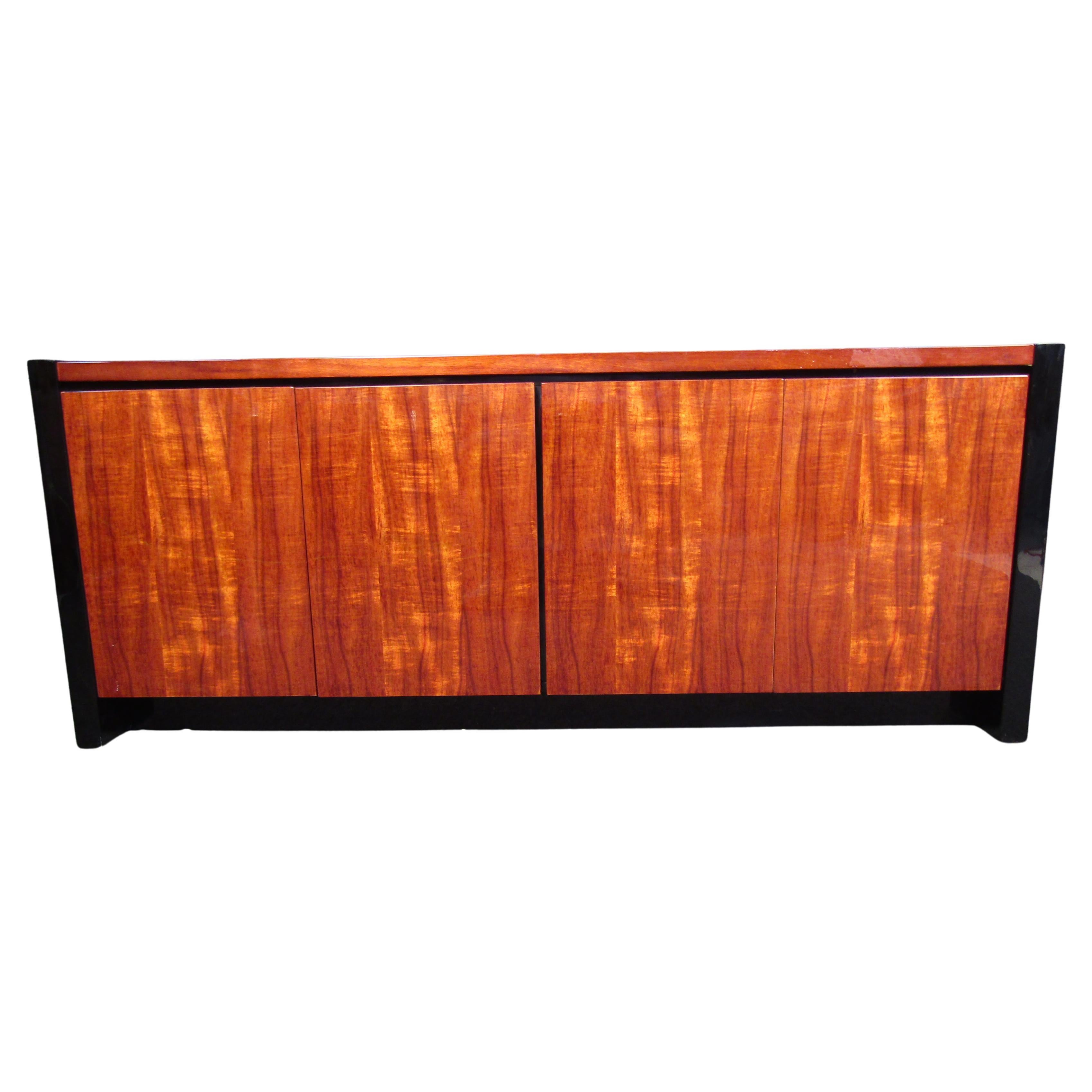 Gorgeous black lacquer and Hawaiian koa wood credenza from the Elan Collection by Henredon. The credenza features stunning and rare koa wood grain and clean, sleek lines. It offers ample room for storage, with three drawers and an adjustable shelf.