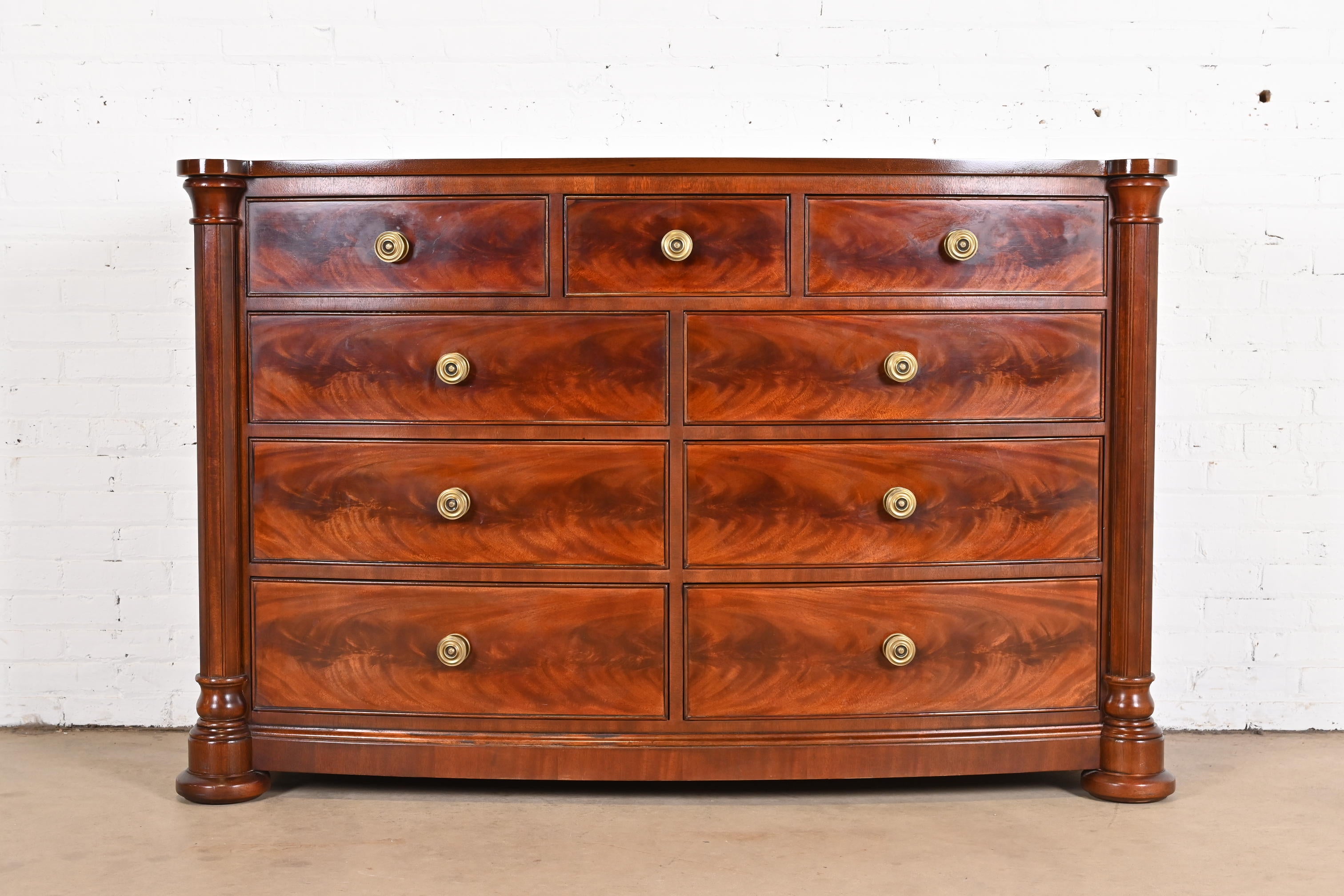 A gorgeous Empire or Georgian style bow front nine-dresser or chest of drawers

In the manner of Ralph Lauren

By Henredon

USA, circa 1980s

Beautiful book-matched flame mahogany, with carved mahogany columns and original brass