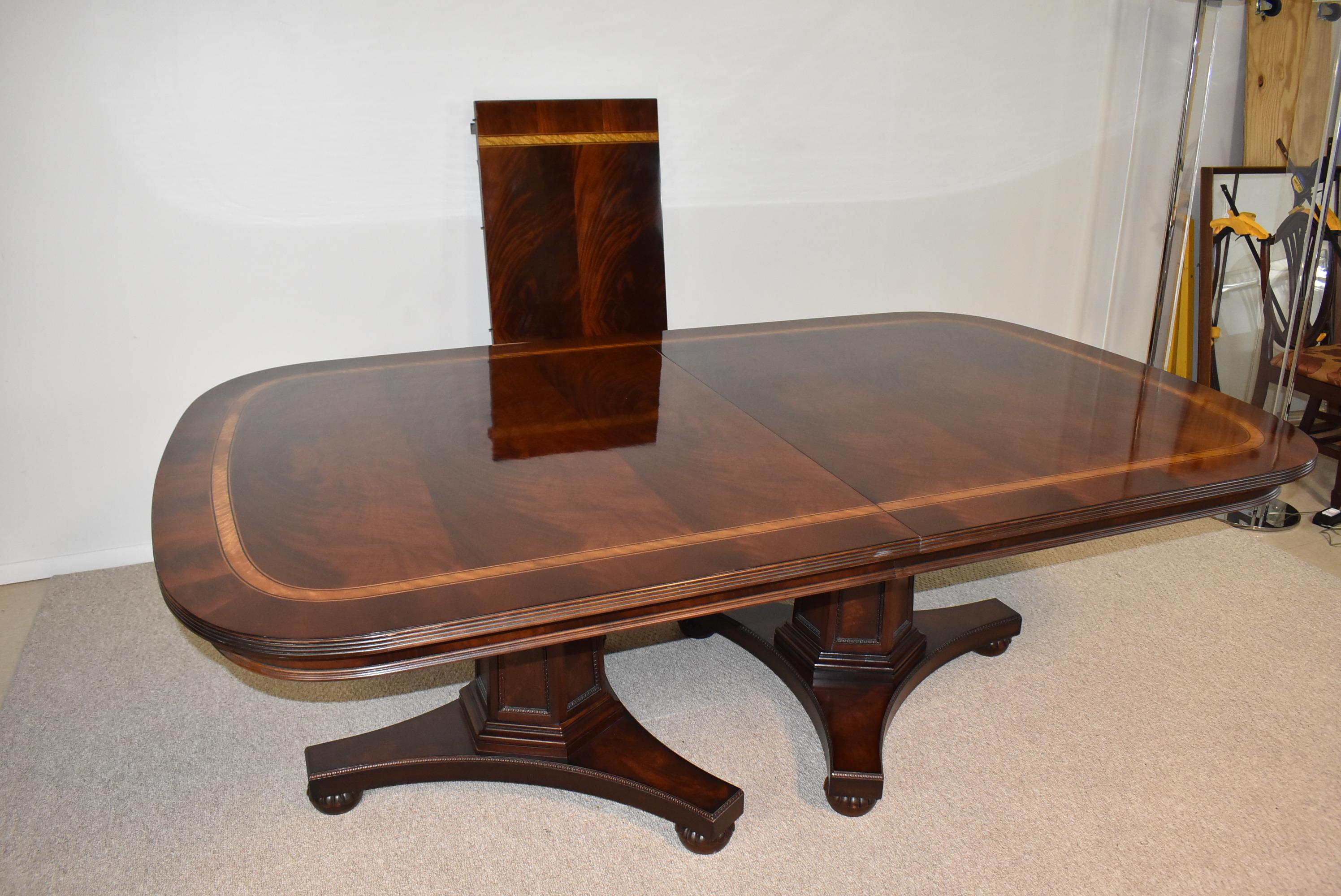Tavolo da pranzo con piano a fasce in mogano fiammato Henredon. Lo stile impero fa parte della collezione Natchez. Due piedistalli con piedini a conchiglia. In ottime condizioni. 86