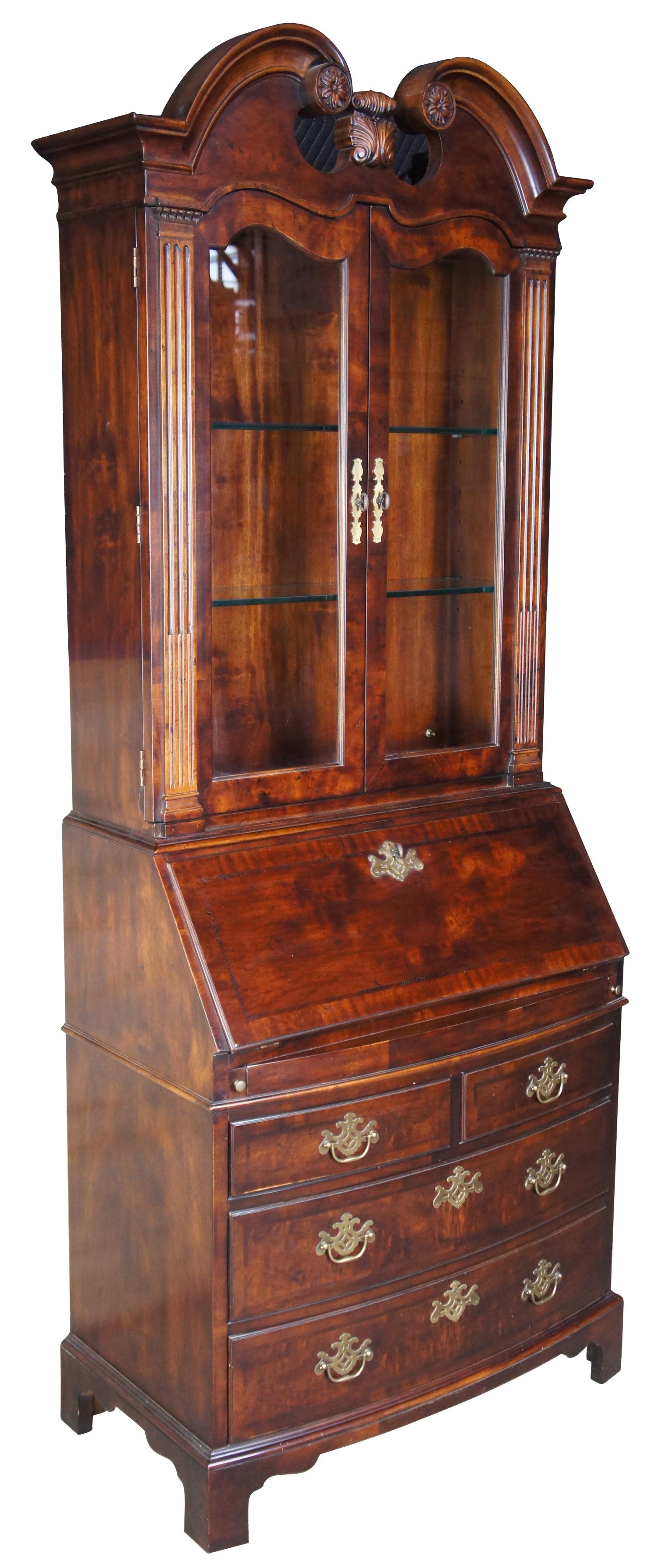 A Chippendale style bow front secretary desk by Henredon from their Folio 10 collection. Made of walnut in the USA in the late 20th century. Upper cabinet features pediment top, two adjustable glass shelves behind glass doors and is lighted. Bottom