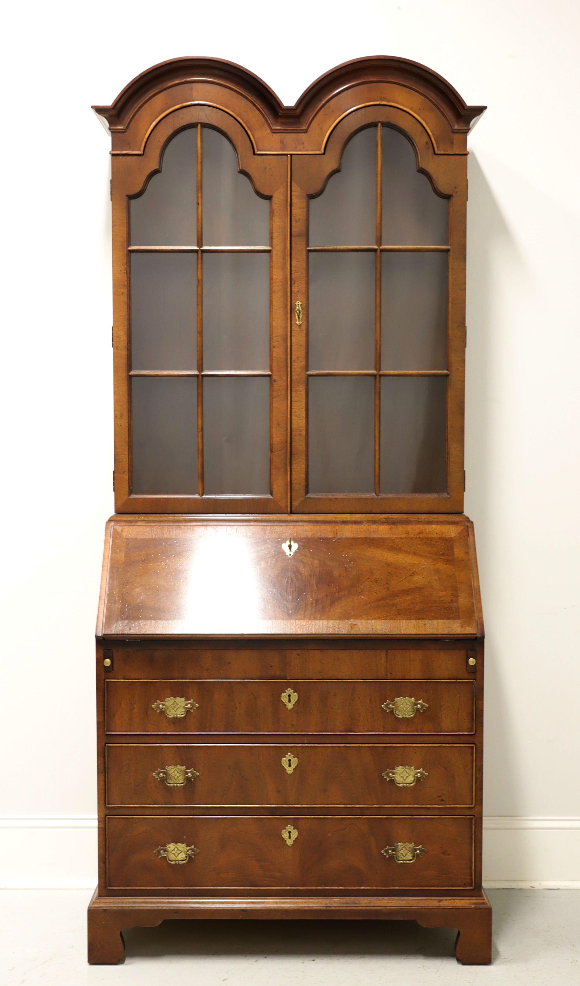 A Chippendale style secretary desk by Henredon, from their Folio 10 Collection. Walnut with brass hardware, double bonnet top, crown moulding, banded desk front and bracket feet. Upper cabinet features two arched doors with paned glass revealing two