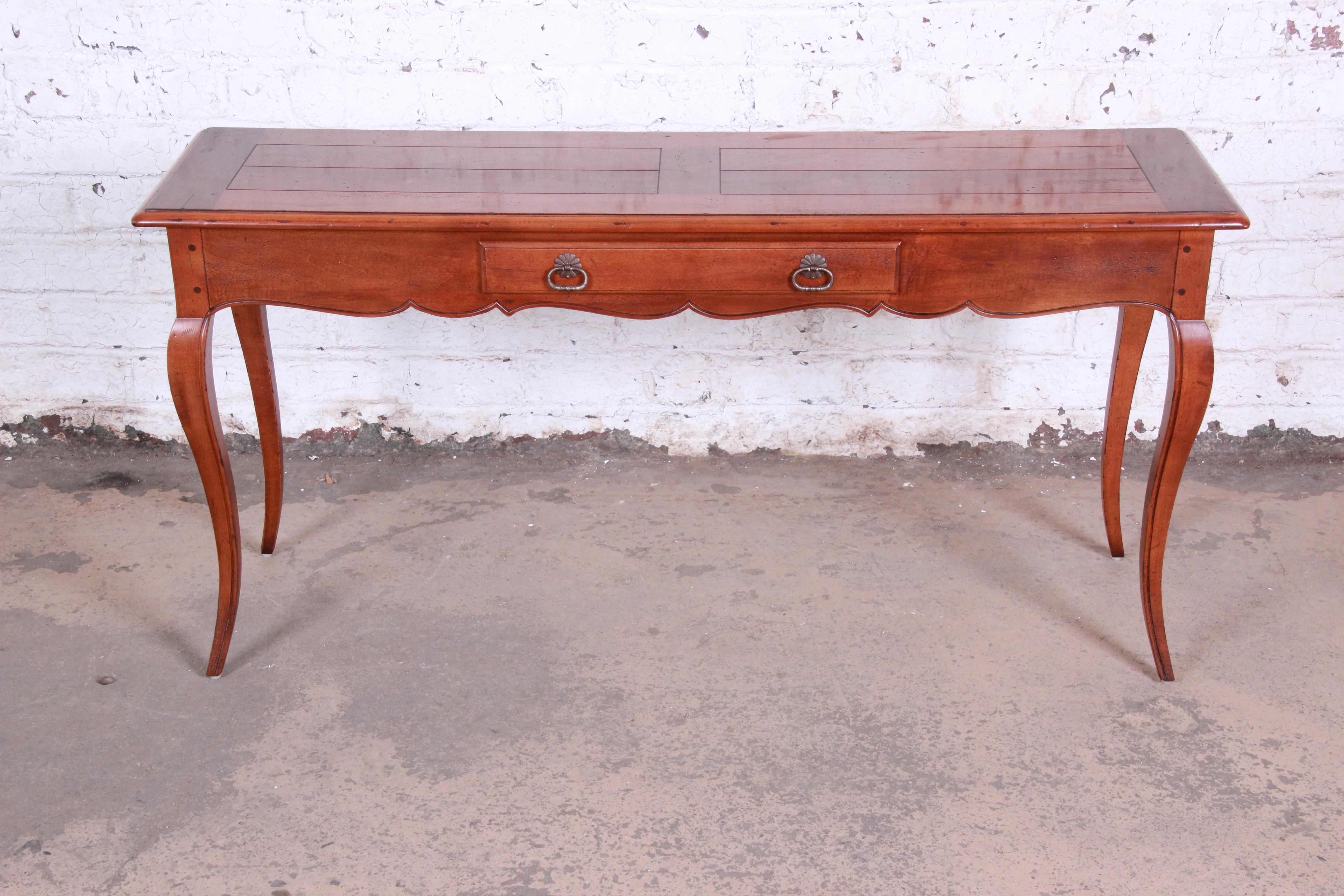 A gorgeous French Provincial Louis XV style console or sofa table by Henredon. The table features solid cherry wood construction with beautiful wood grain and tall cabriole legs. It has a single drawer for storage, and the original Henredon label is