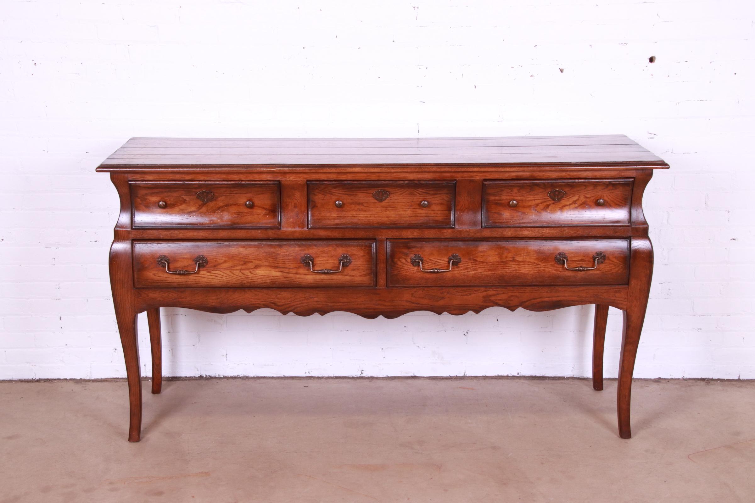 A beautiful French Provincial Louis XV style bombay form sideboard, credenza, or buffet

By Henredon

USA, Late 20th Century

Carved oak, with original brass hardware.

Measures: 72