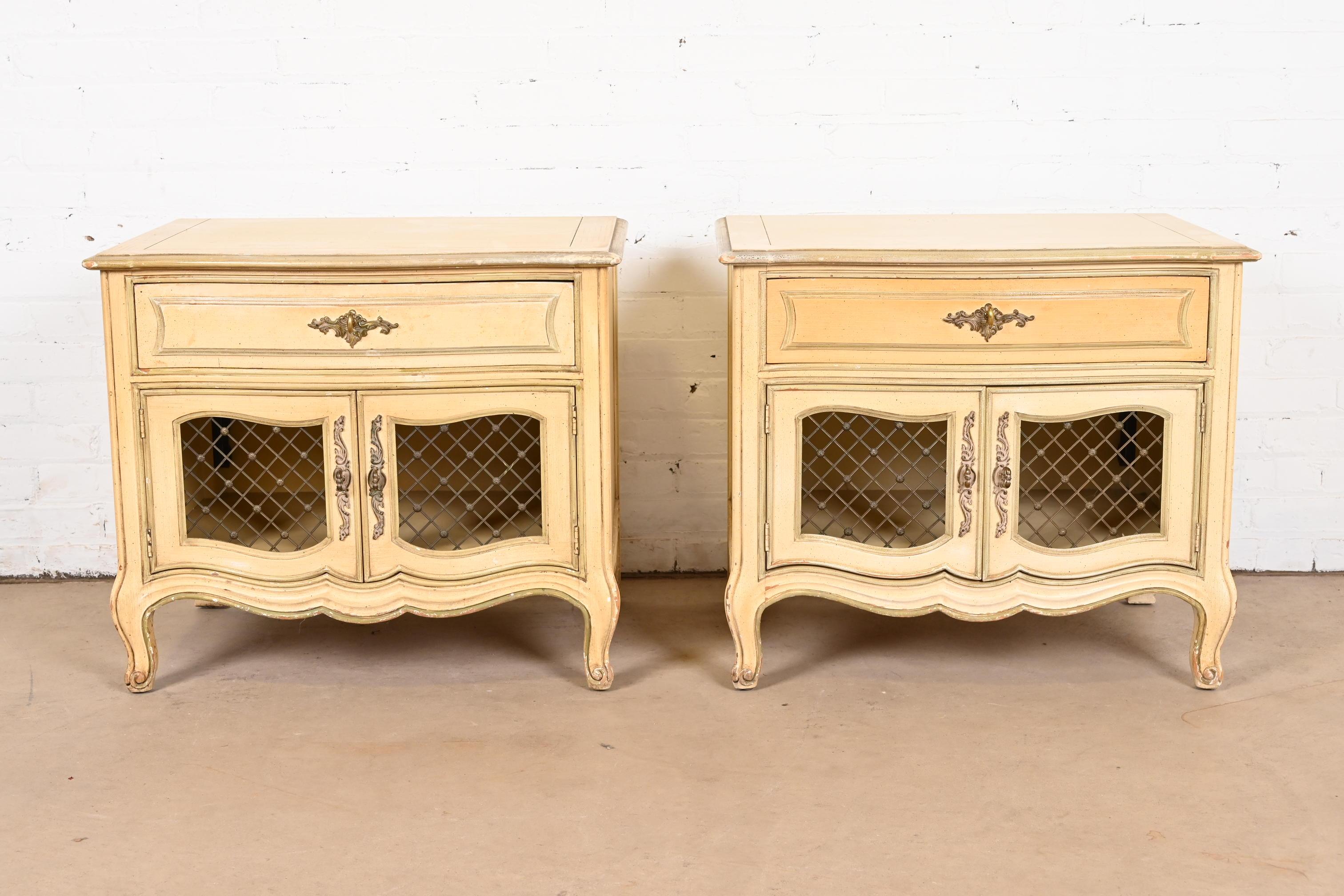 A stylish pair of French Provincial Louis XV style nightstands

By Henredon

USA, Circa 1960s

Carved cream lacquered walnut, with olive green trim, and original brass hardware.

Measures: 28