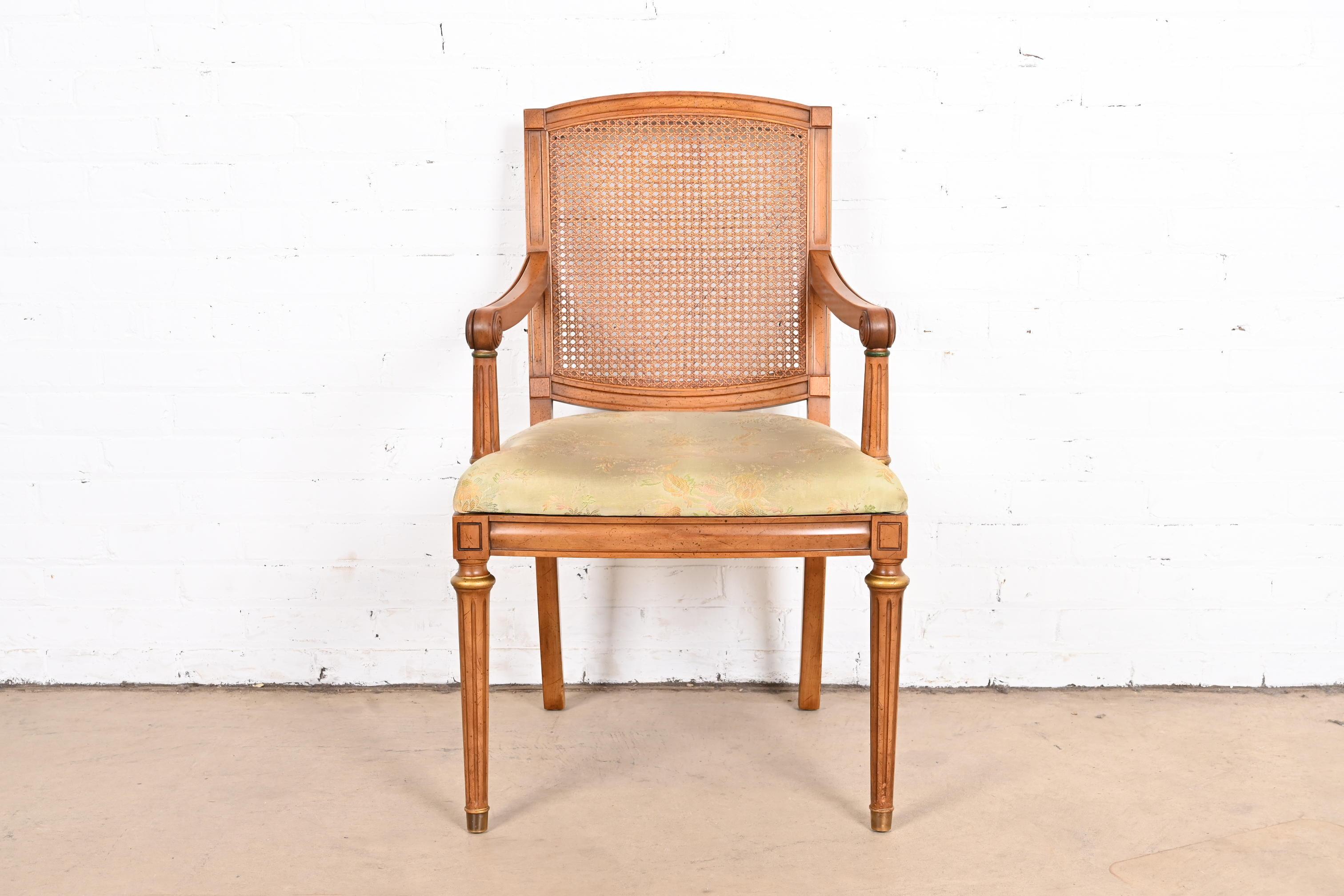 A gorgeous French Regency Louis XVI style armchair

By Henredon

USA, circa 1960s

Sculpted cherry wood frame, with caned seat back, upholstered seat, gold gilt details, and brass-capped feet.

Measures: 22.25