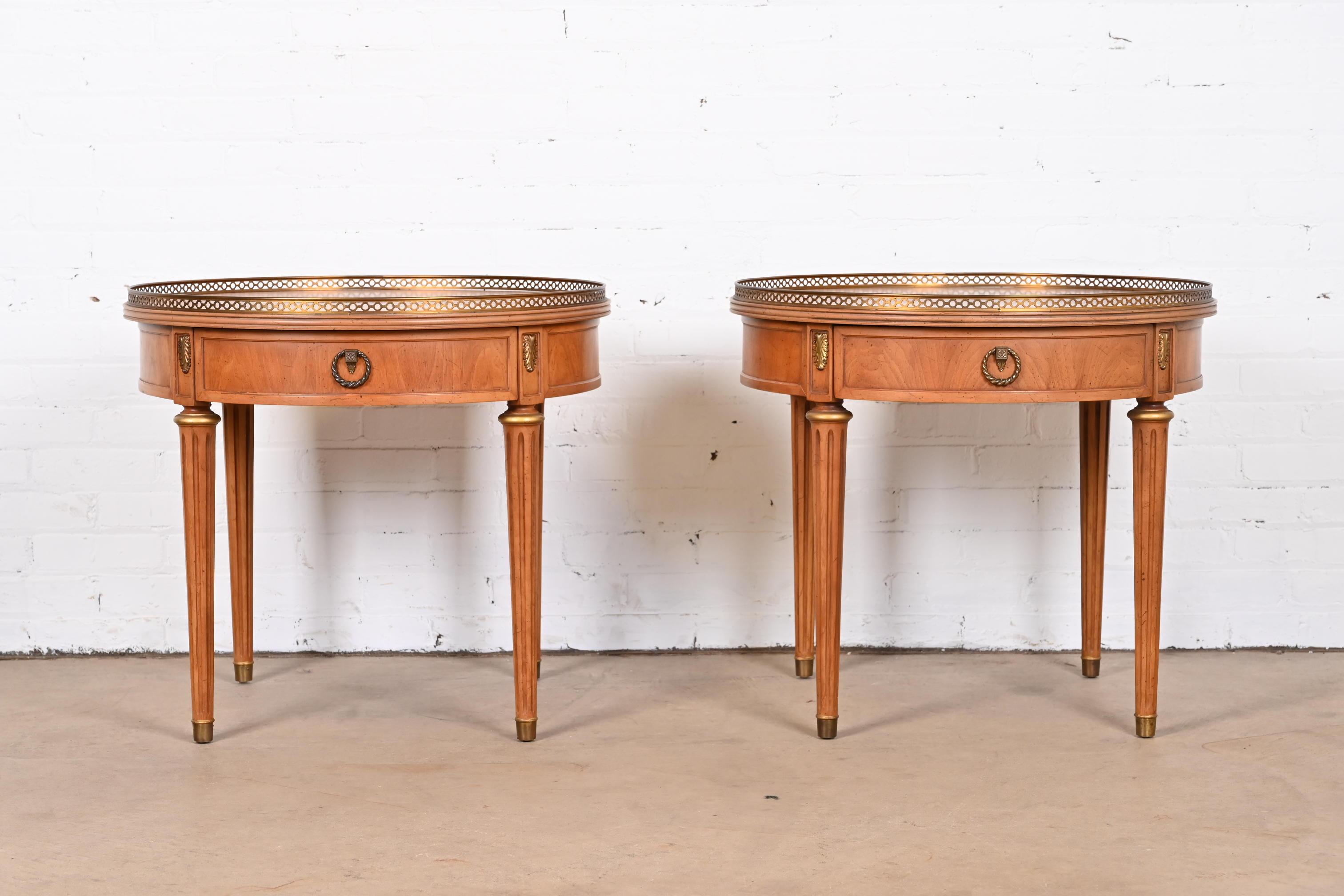 A gorgeous pair of French Regency Louis XVI style gueridons, side tables, or nightstands

By Henredon

USA, 1960s

Beautiful book-matched fruitwood, with original brass pulls, brass gallery and mounted ormolu, and brass-capped