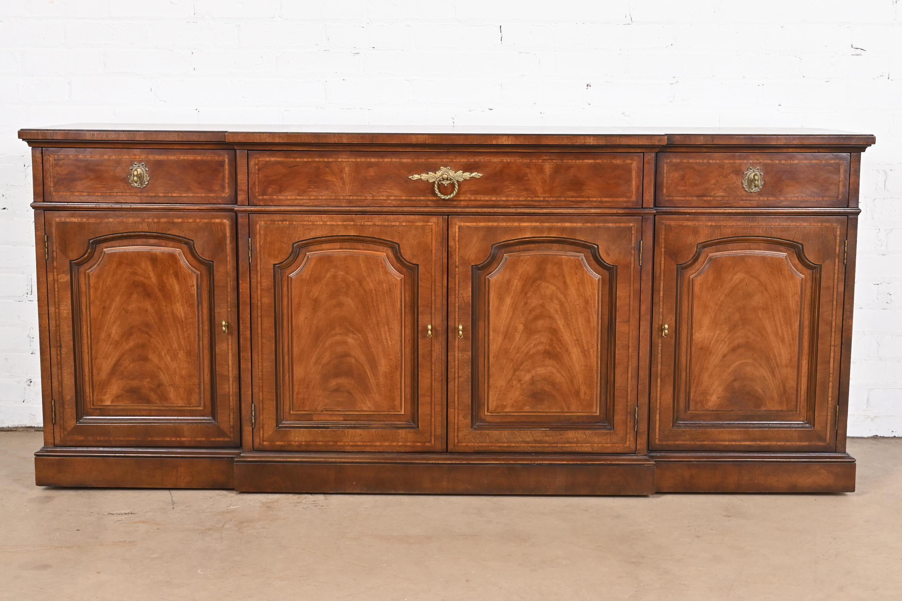 A gorgeous Georgian or French Regency Louis XVI style breakfront sideboard, credenza, or bar cabinet

By Henredon

USA, Circa 1980s

Beautiful book-matched mahogany, with satinwood inlay, and original brass hardware.

Measures: 70