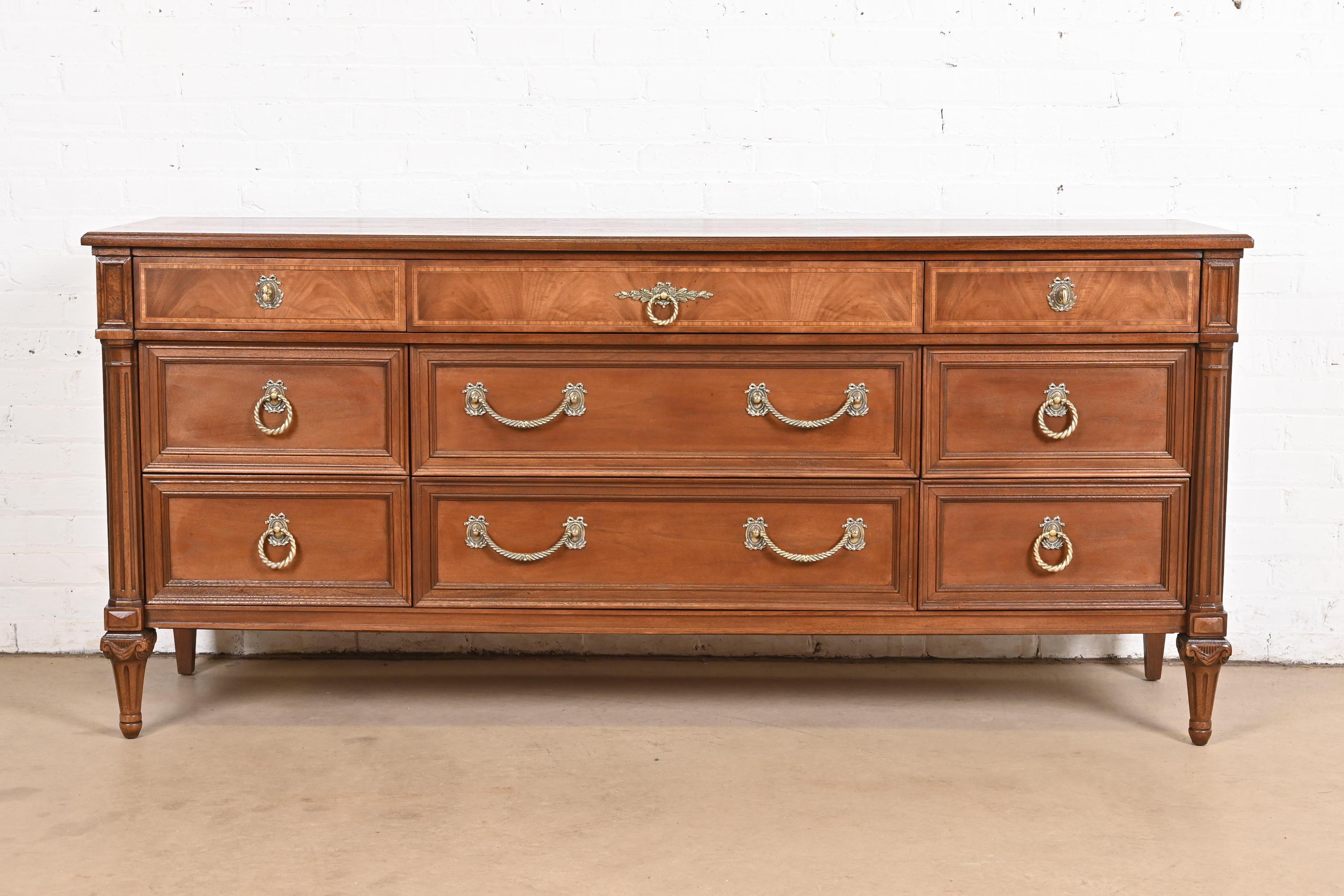 A gorgeous French Regency Louis XV style nine-drawer long dresser or credenza

By Henredon

USA, Circa 1960s

Carved mahogany, with satinwood inlay, and original brass hardware.

Measures: 72