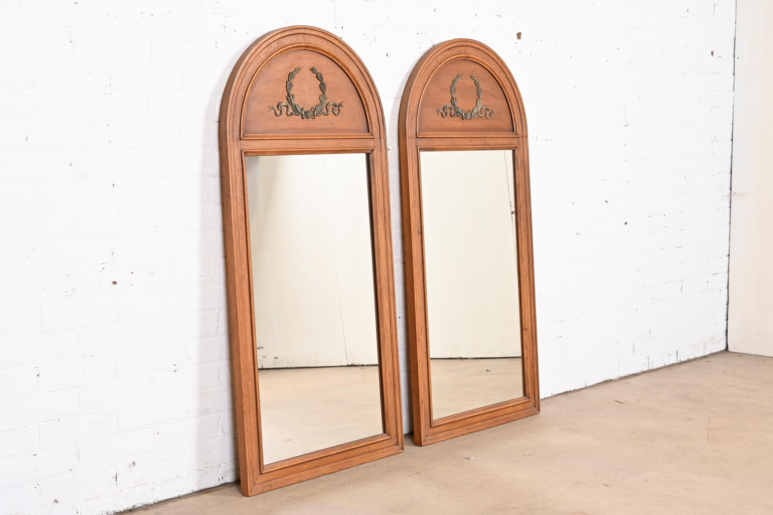 A gorgeous pair of French Regency Louis XVI style tall arched wall mirrors

By Henredon

USA, 1965

Walnut frames, each adorned with mounted brass wreaths.

Measures: 23.38