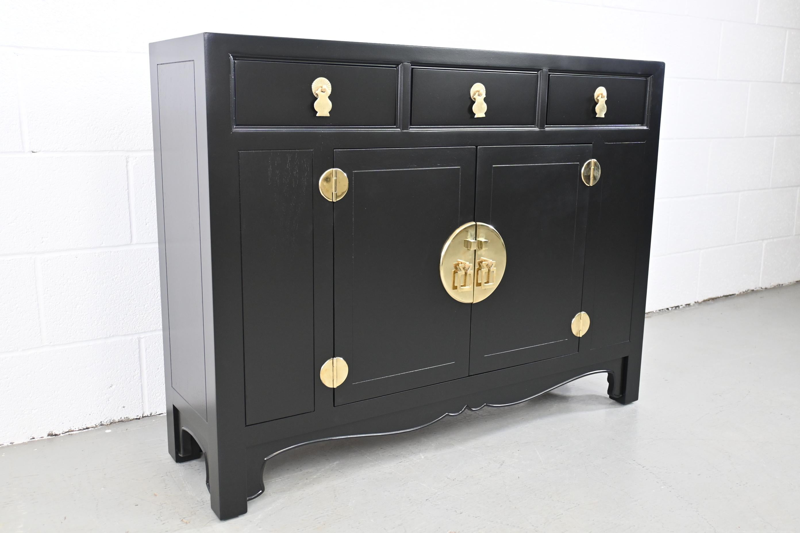 Henredon Asian Inspired Black Lacquered Petite Sideboard with Brass Accents.

Henredon, USA, 1970s

Measures: 42 Wide x 12 Deep x 32.25 High

Asian style black lacquered sideboard with three drawers and one cabinet.

Professionally