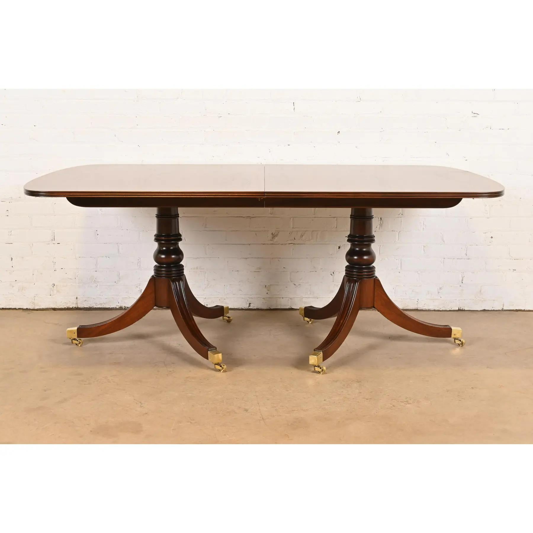 Exceptionnelle table de salle à manger à double piédestal de style géorgien ou régence.

Par Henredon

USA, Circa 1980

Magnifique plateau en acajou assorti au livre, avec bandes de bois satiné, piédestaux en acajou massif sculpté, et pieds coiffés