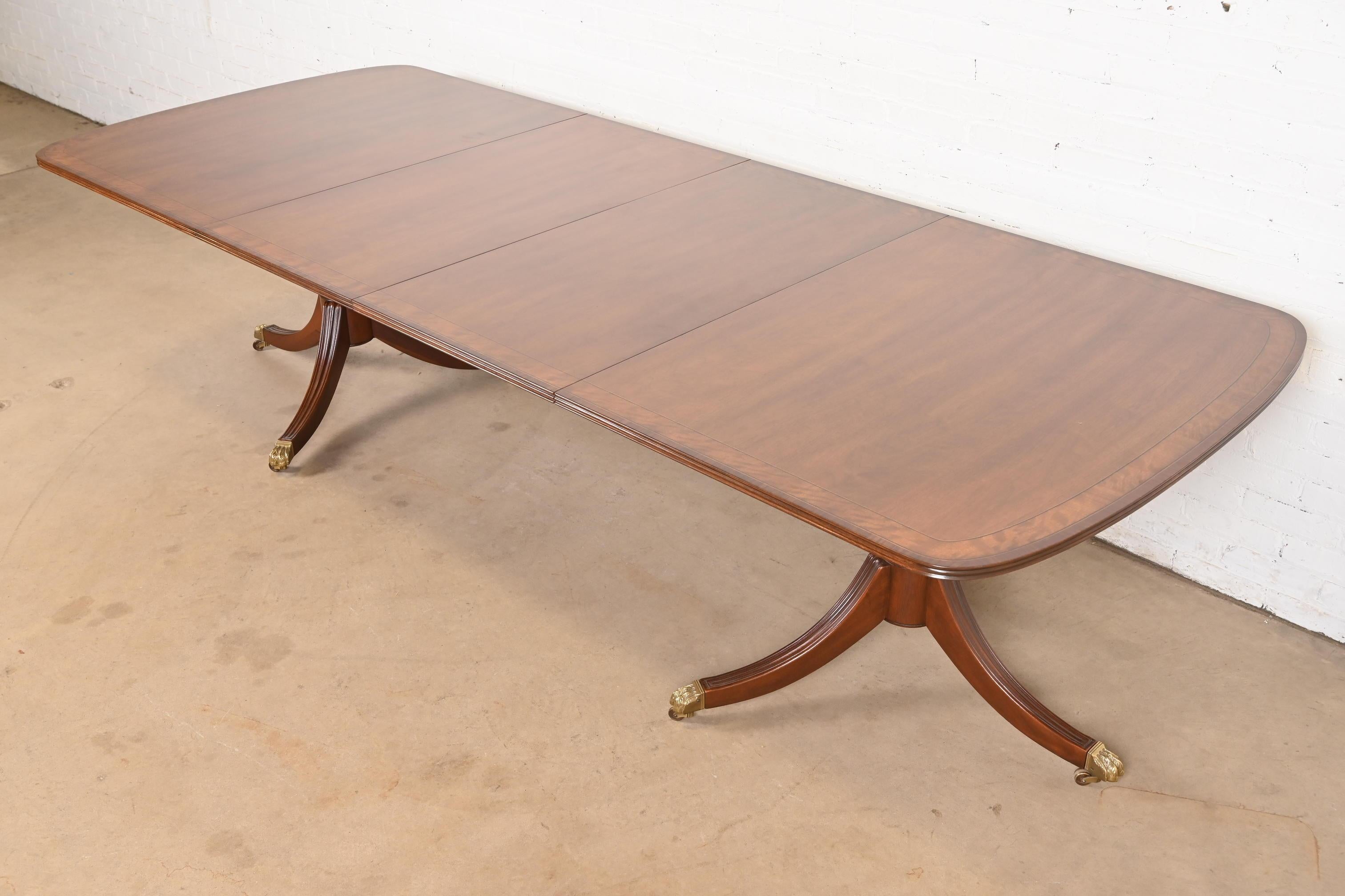 An exceptional Georgian or Regency style double pedestal extension dining table

By Henredon

USA, Circa 1980s

Gorgeous mahogany, with satinwood banding, carved mahogany pedestals, and brass paw feet on brass casters.

Measures: 68.25