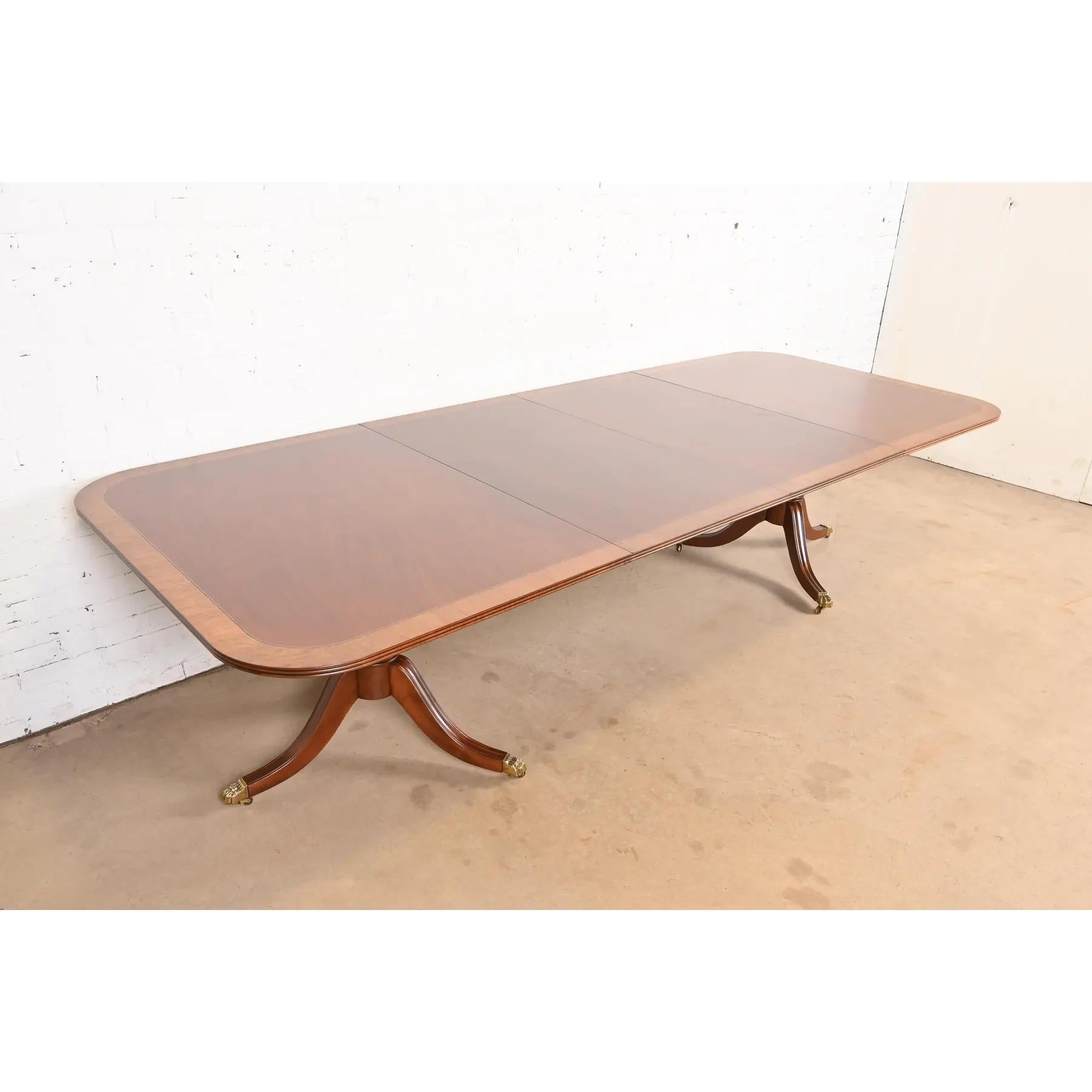 An exceptional Georgian or Regency style double pedestal extension dining table

By Henredon

USA, Late 20th Century

Gorgeous mahogany, with satinwood banding, carved solid mahogany pedestals, and brass paw feet on brass casters.

Measures: 68.25