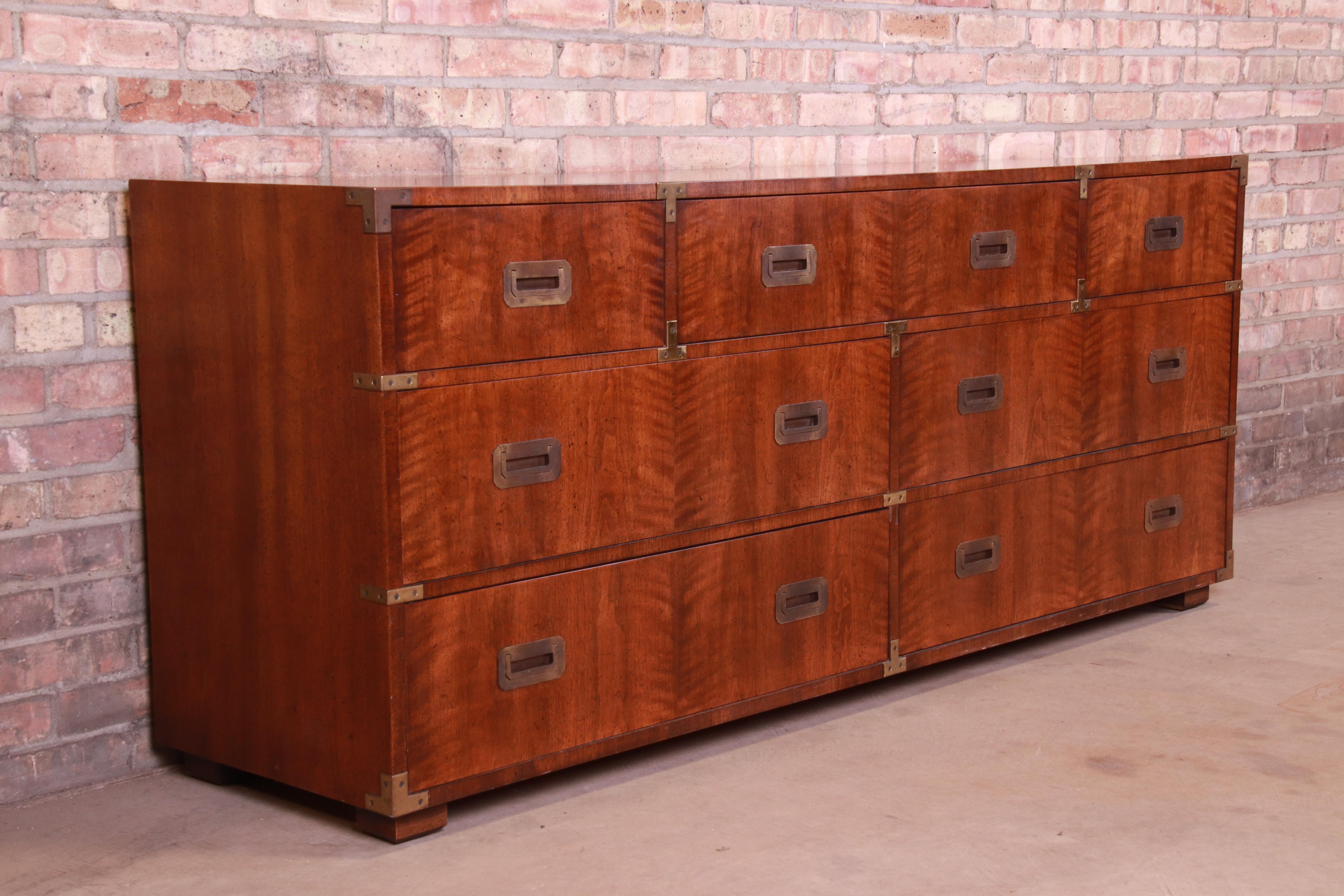 A gorgeous midcentury Hollywood Regency Campaign style seven-drawer long dresser or credenza

By Henredon

USA, circa 1970s

Book-matched mahogany, with brass hardware and accents.

Measures: 72