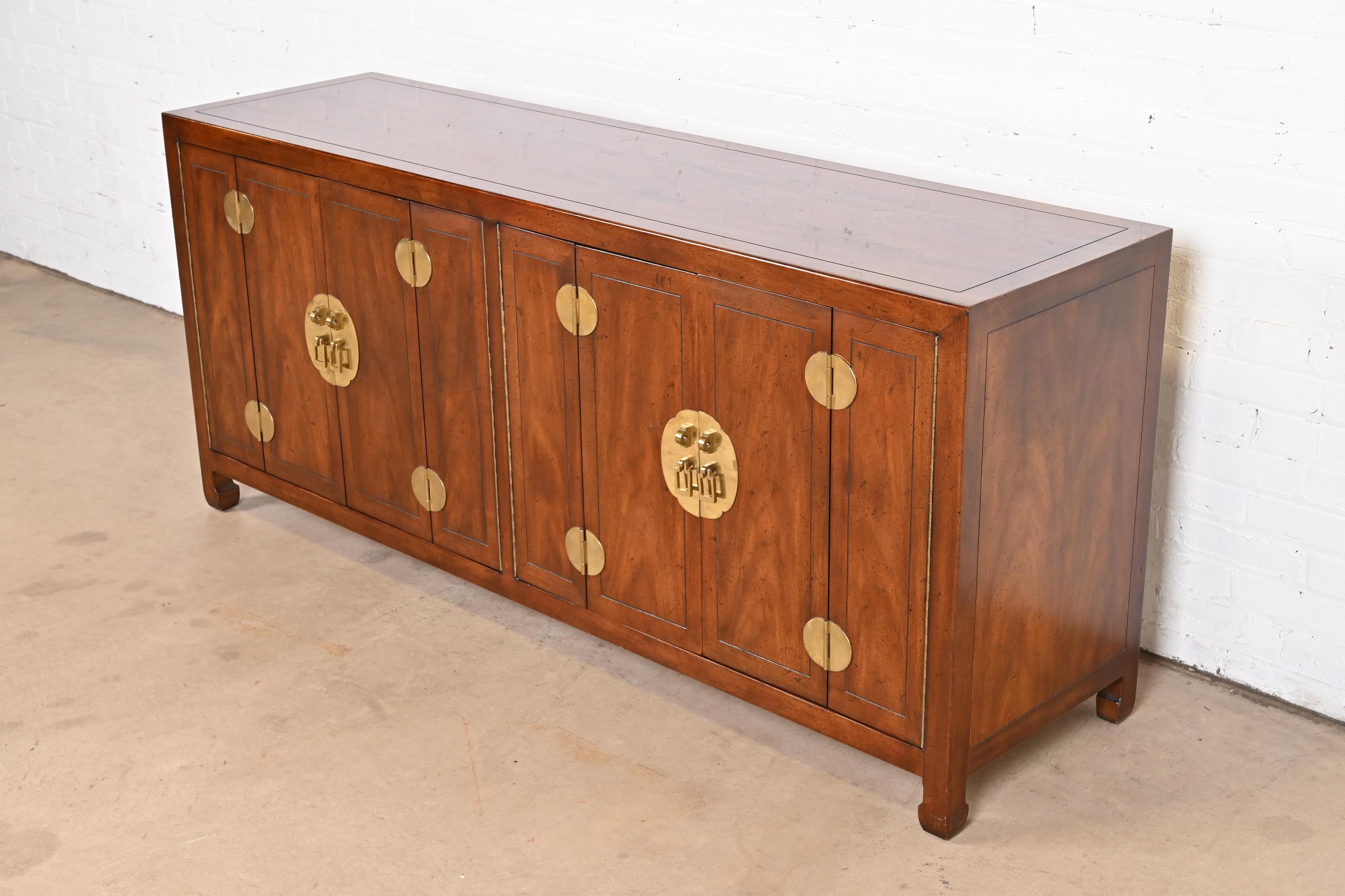An exceptional mid-century Hollywood Regency Chinoiserie sideboard, credenza, or bar cabinet

By Henredon

USA, Circa 1970s

Book-matched mahogany, with Asian-inspired brass hardware and accents.

Measures: 70