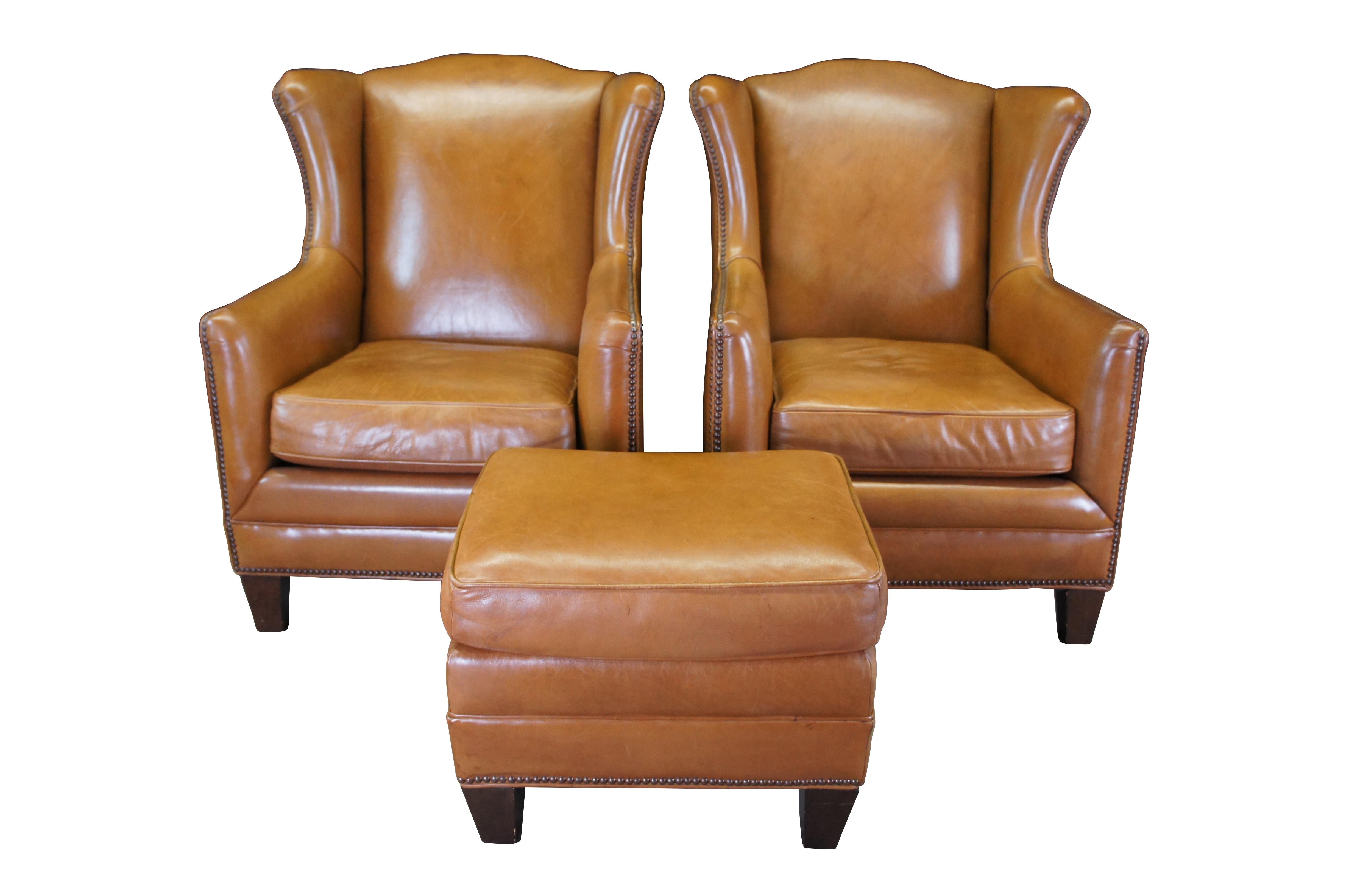 Set of two vintage Henredon club / lounge / library wingback arm chairs and ottoman featuring traditional styling with brown leather upholstery and nailhead trim.

Dimensions:
34