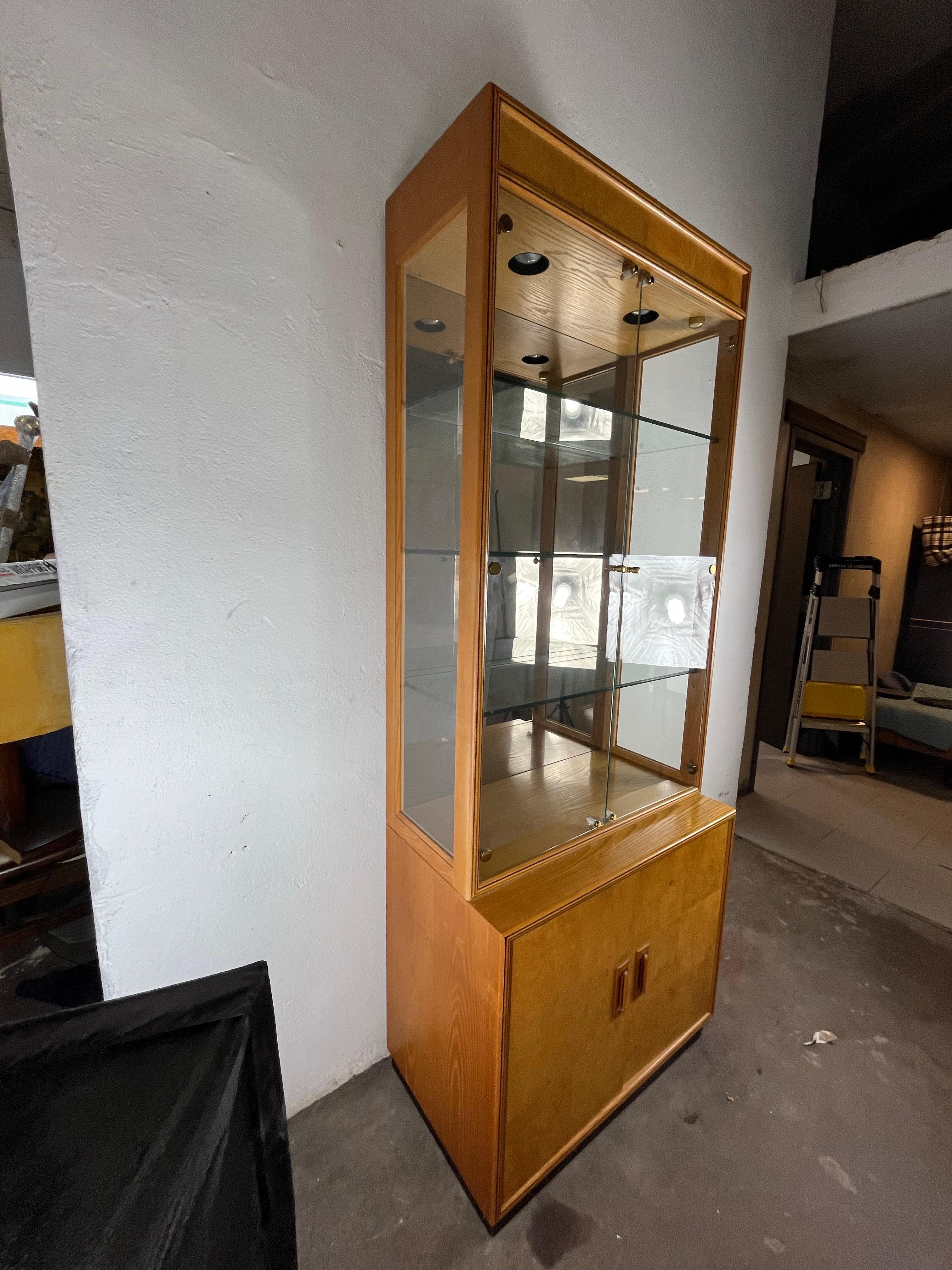 From the Henredon Scene Two Collection this stunning burlwood display cabinet features mirror backed glass cases with recessed lighting. 3 glass shelves with plate grooves. There are hand inlaid handles and an ebonized base. In the styling of Milo