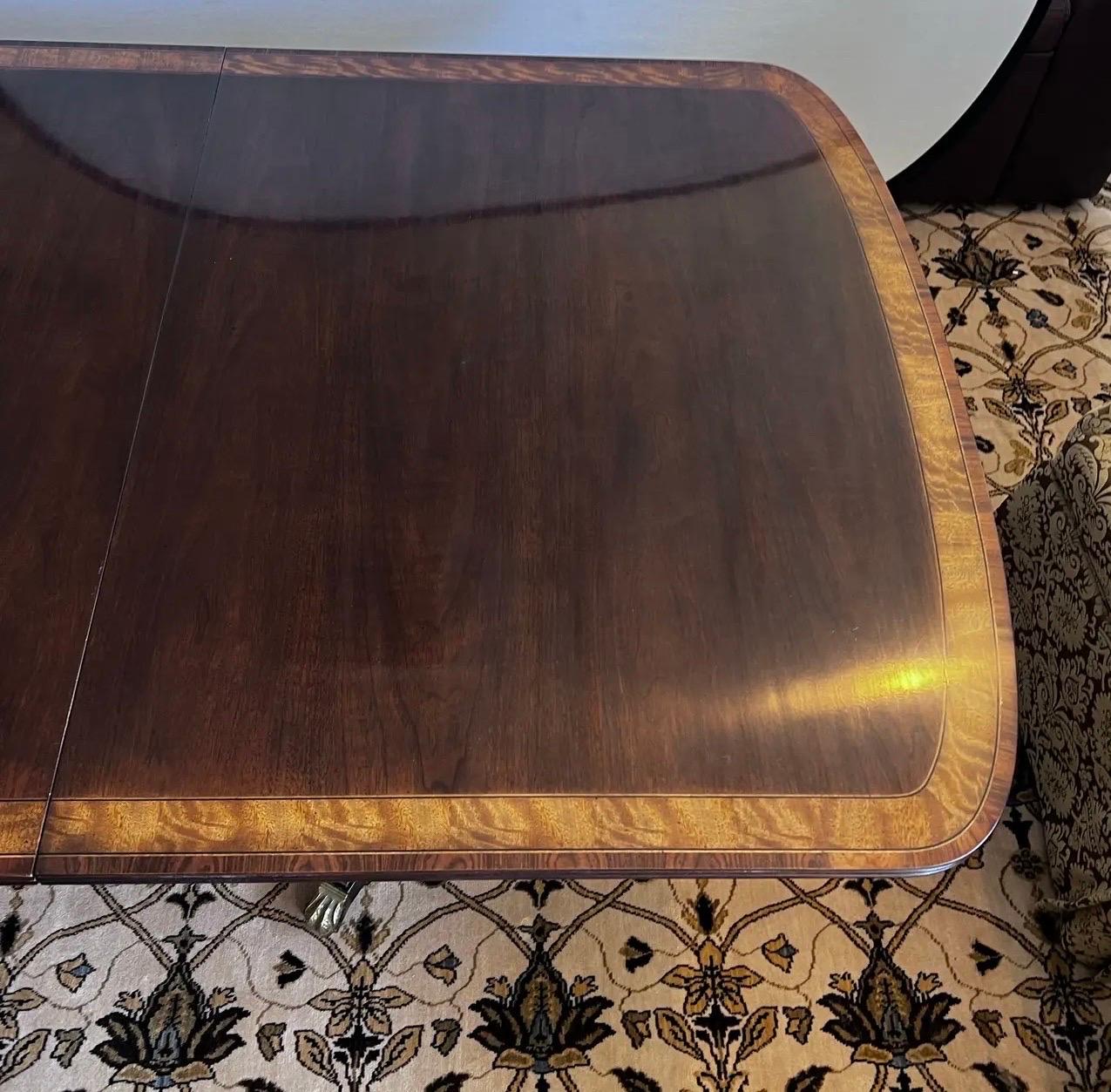 Magnificent Henredon double pedestal inlay dining table supported on double pedestals with brass paw feet and three 22