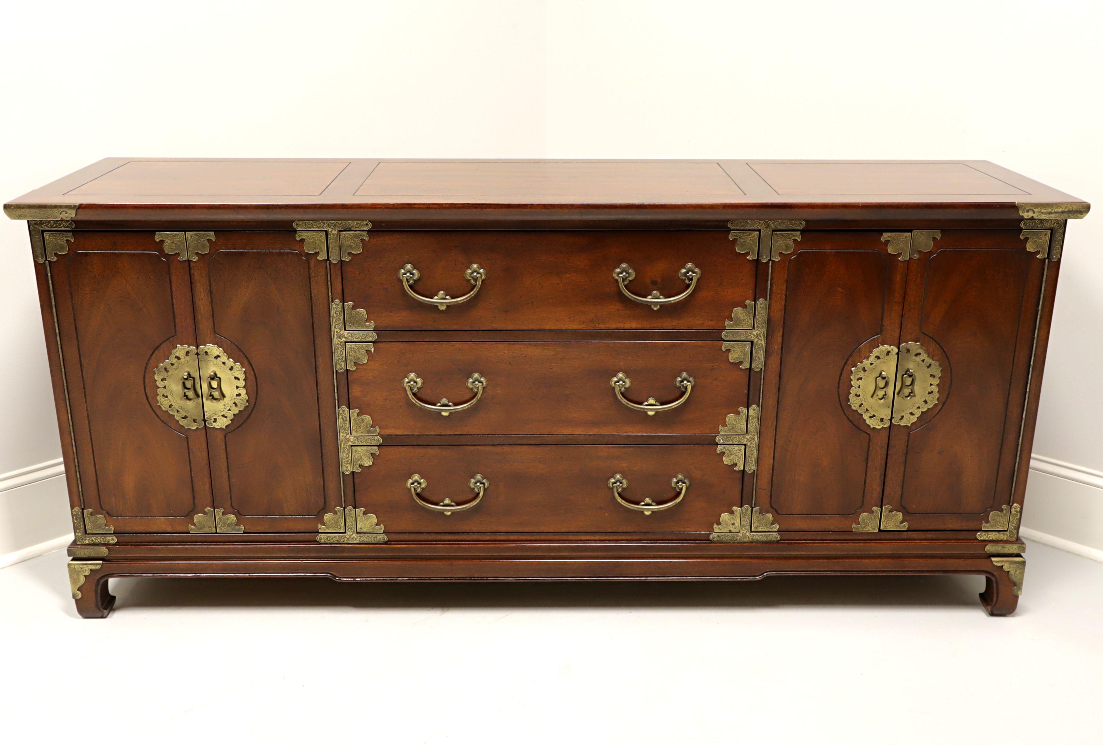 A credenza in the Japanese Tansu Campaign style by Henredon. Mahogany with banded top, brass hardware and brass accents. Features three center drawers of dovetail construction, flanked by two side cabinets with dual doors reveailing storage areas