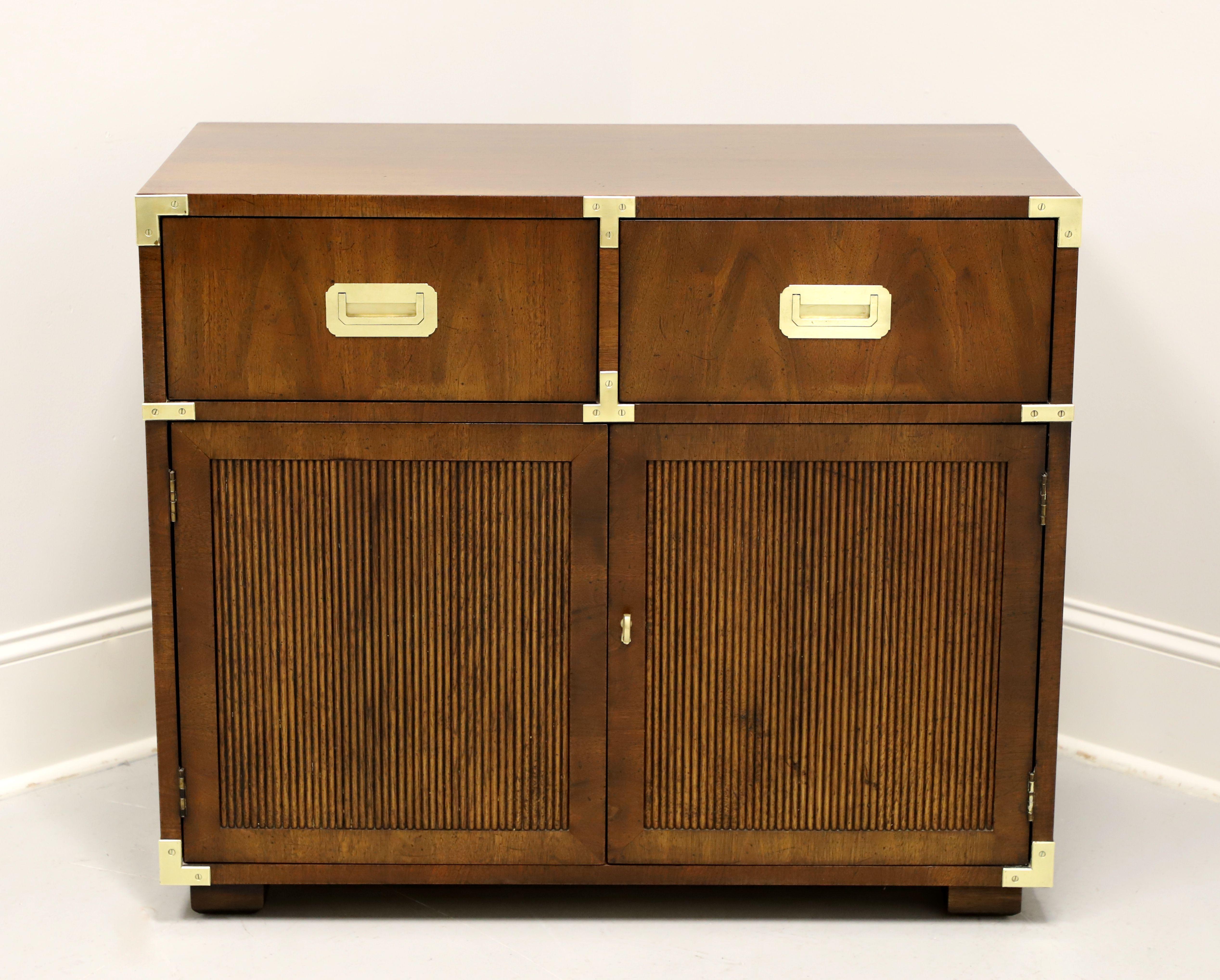 A campaign style console cabinet by Henredon. Walnut with a slightly distressed finish, brass accents & hardware, smooth edge to top, ribbed door fronts, and block feet. Features two drawers of dovetail construction over a lower two door cabinet