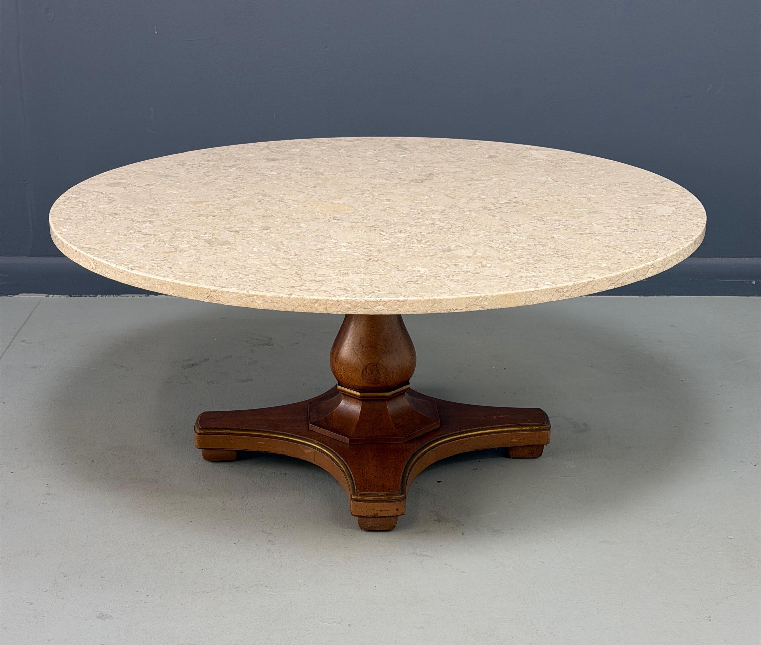 Cette élégante table basse Henredon présente un remarquable plateau rond en pierre fossile, mettant en valeur des motifs minéraux naturels dans des tons chauds et neutres. La surface substantielle en pierre repose sur un socle en bois sculpté à la
