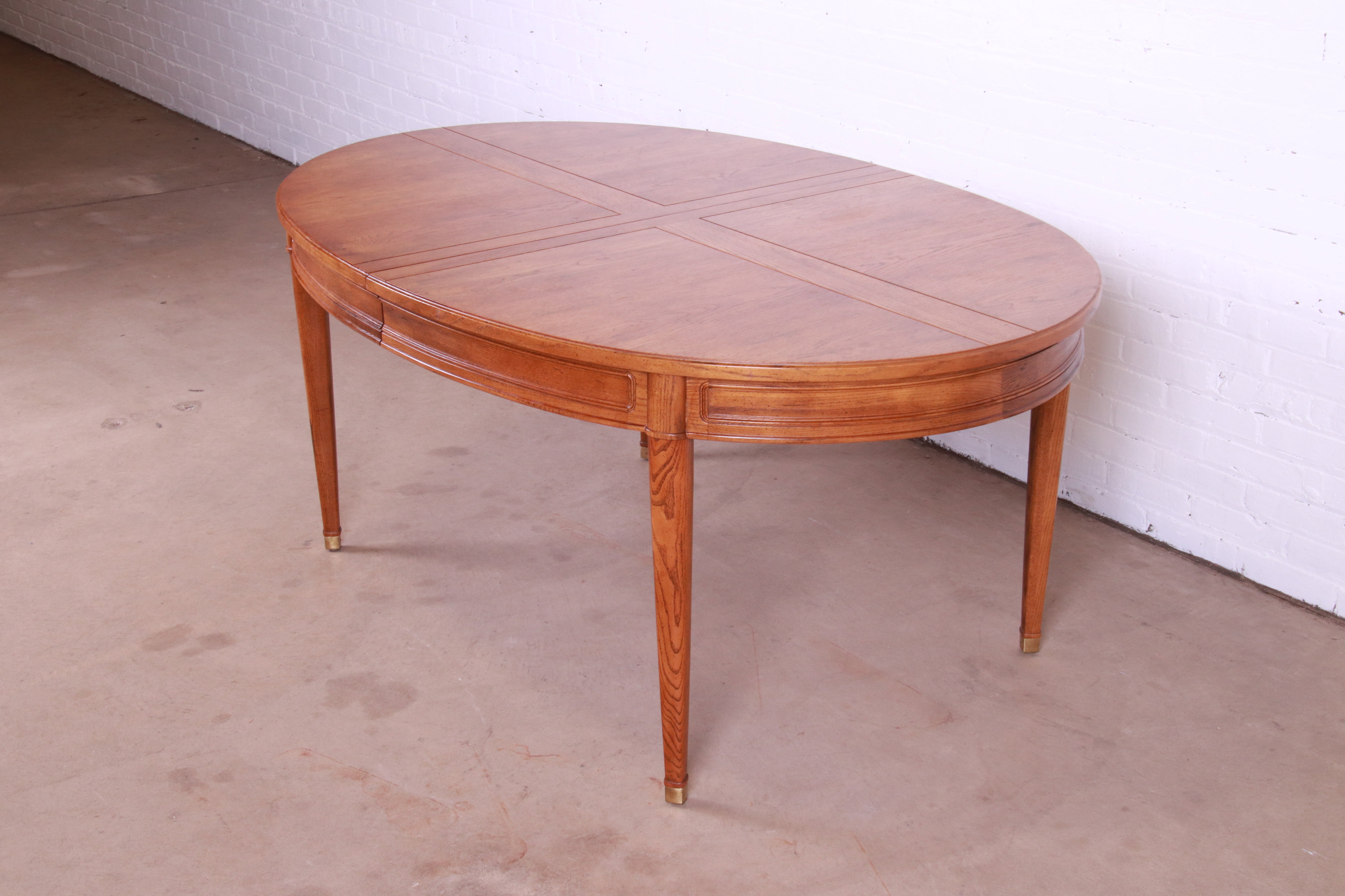 A beautiful Mid-Century Modern French Regency style extension dining table

By Henredon

USA, Circa 1970s

Oak, with brass capped feet.

Measures: 65