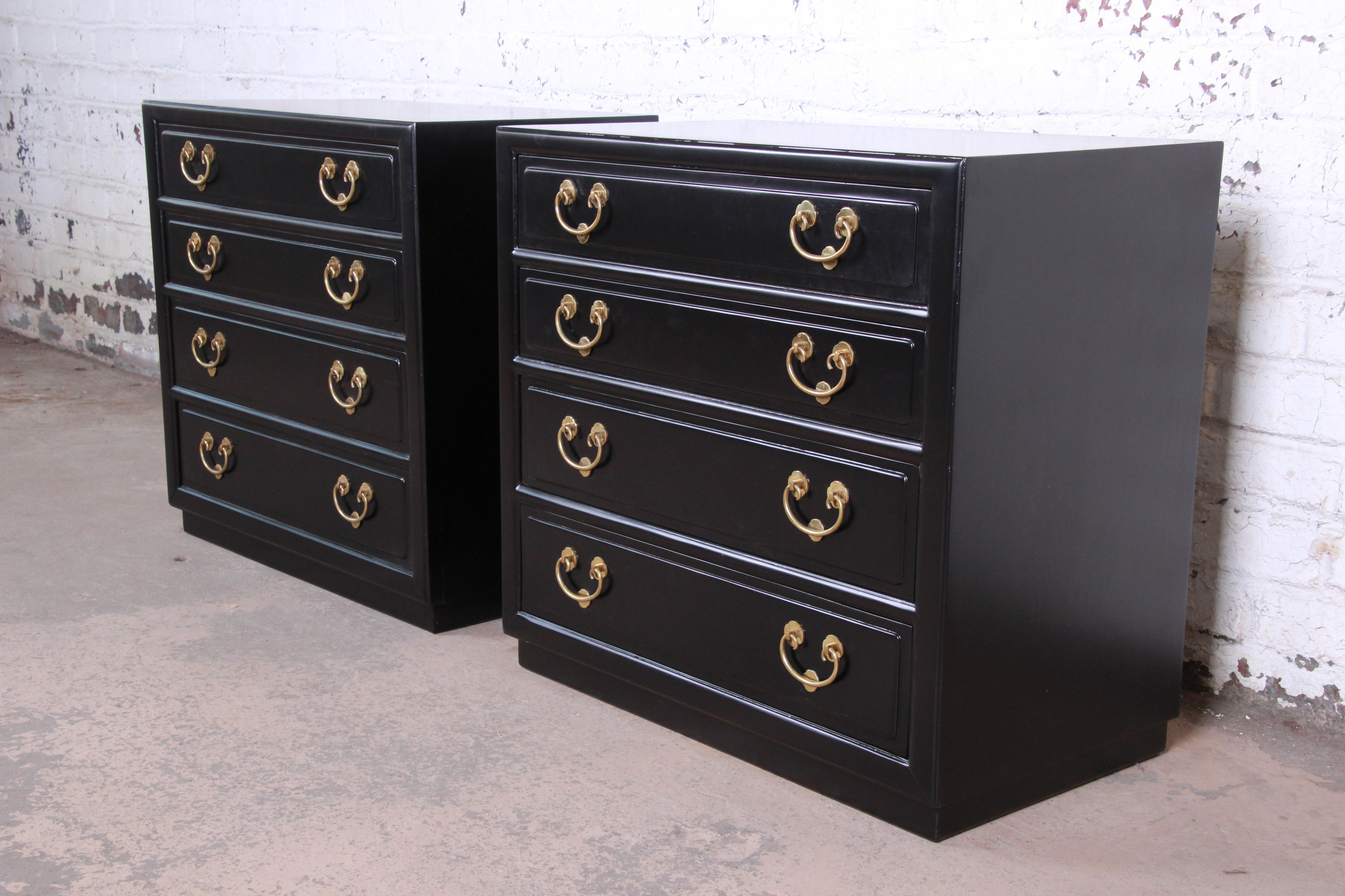 A gorgeous pair of Hollywood Regency chinoiserie bedside chests or dressers by Henredon. The chests have been expertly refinished in ebony, and they feature the original Asian-inspired brass hardware. They offer ample storage, each with four