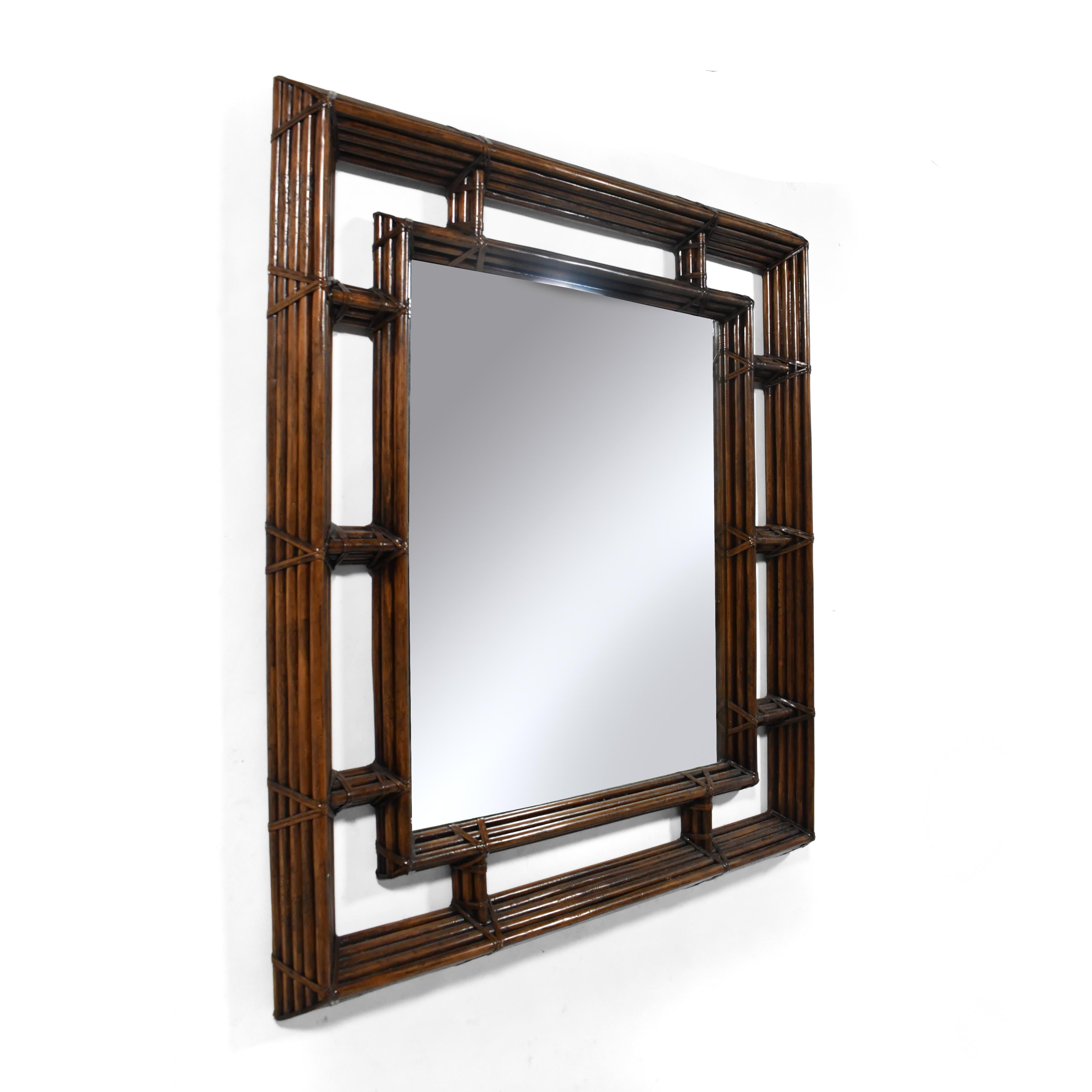 This large, impressive mirror by Henredon framed in multiple stacked bands of rattan has incredible presence and depth. The interior frame has five bands, the outer frame has nine. The rattan is bound, not in cane, but in rawhide leather– a