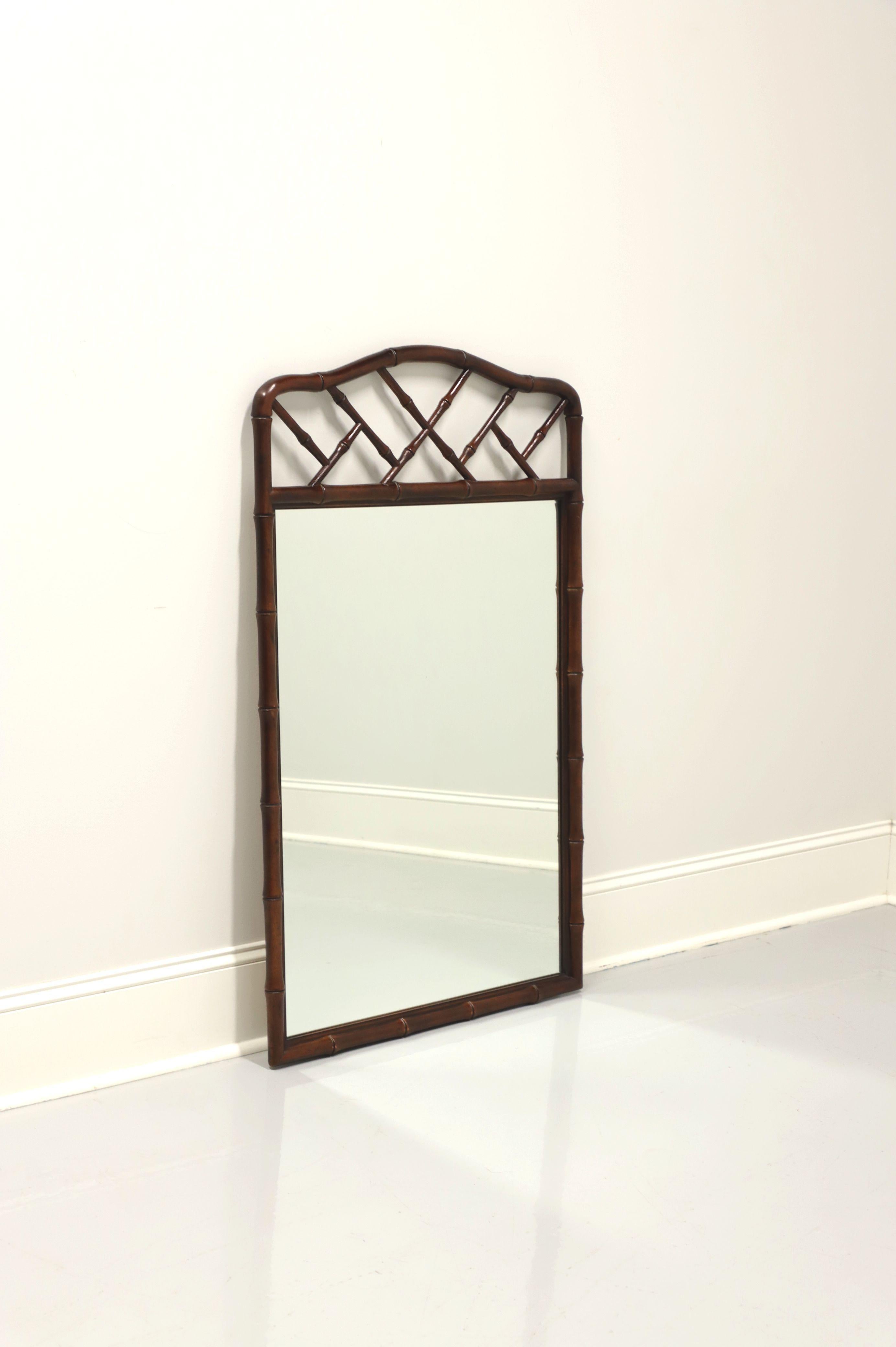 A Pan Asian style wall mirror by Henredon. Mirror glass and faux bamboo frame with arched fretwork top. Made in North Carolina, USA, circa 1973. 

Style #: 4-8101

Measures: 29 W 1.5 D 48 H, Weighs Approximately: 30 lbs

Exceptionally good condition