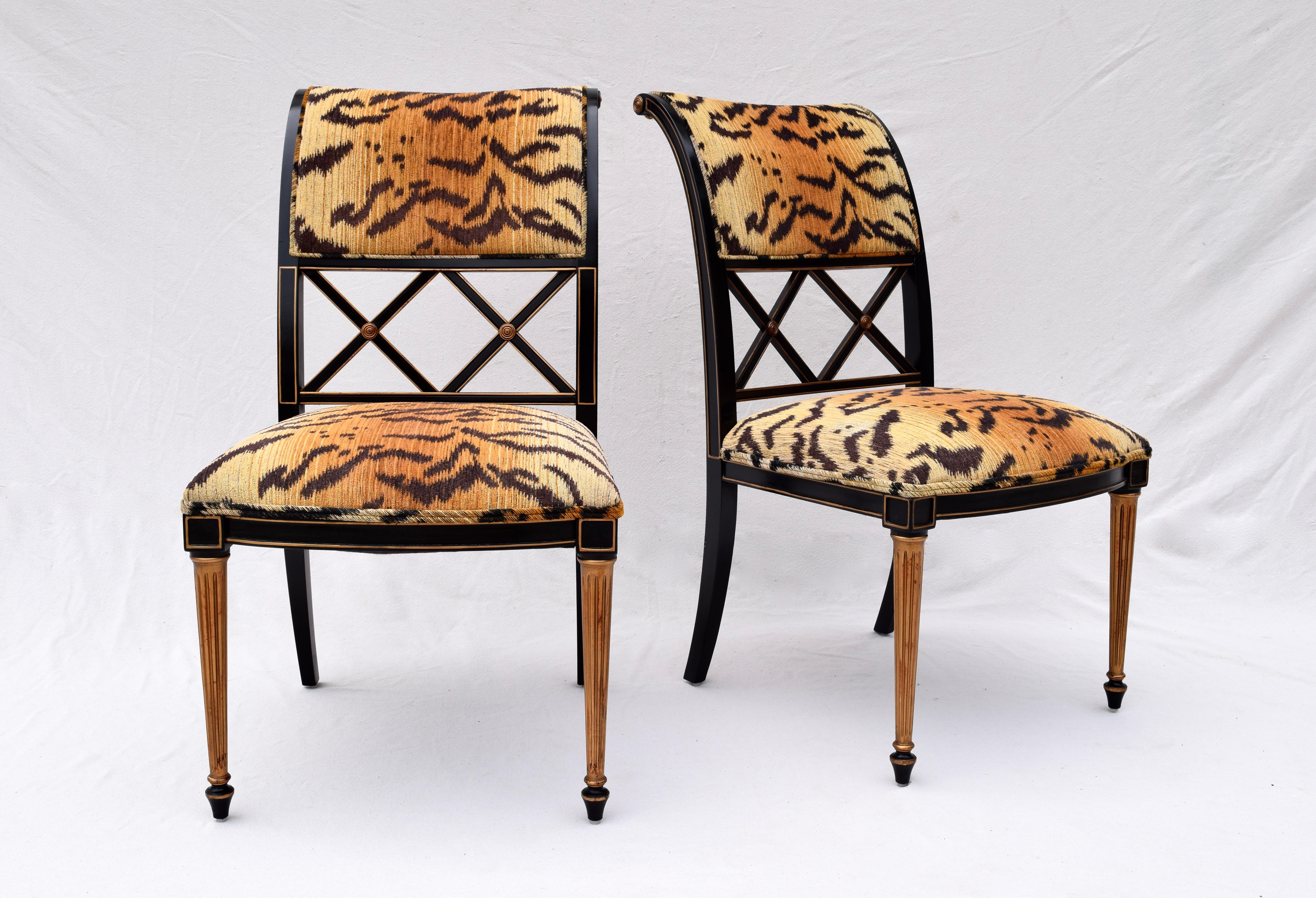 A pair of Regency style dining chairs attributed to Henredon Furniture in the manner of Dorothy Draper. Exceptional sculptural form with double X back splat design lacquered in black with gold accents, upholstered in striking Tigre Chenille.