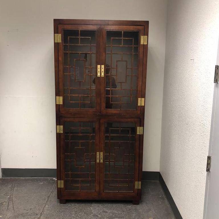 A Henredon display case. The cabinet has a distinct Asian flare. There are four glass shelves and all of them have an etched ridge for holding plates upright. Both the top and the bottom are out fitted two lights for show casing your treasures. The