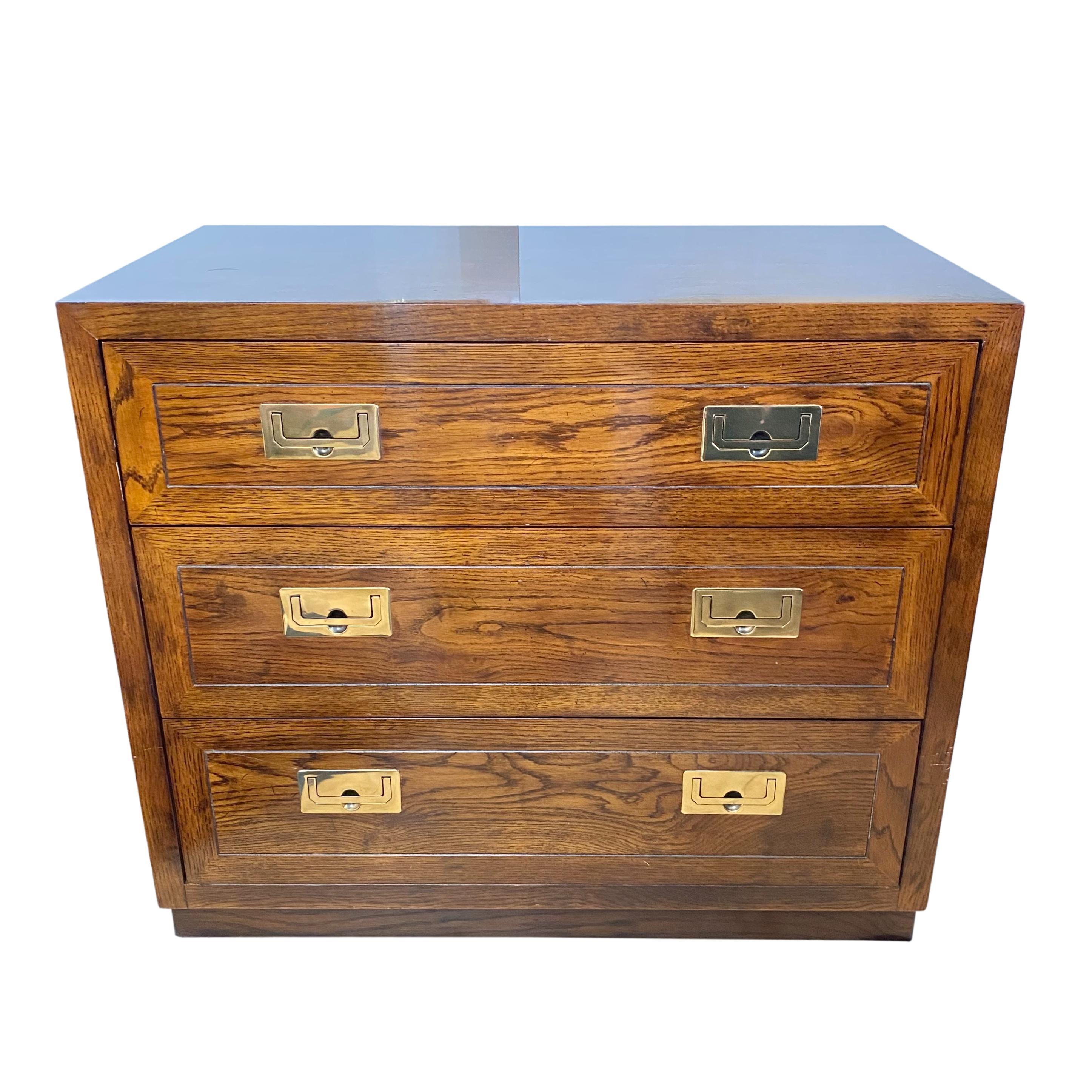 A vintage three drawer campaign style bachelor's chest or nightstand by Henredon. Oak finish with brass hardware.

Dimensions: 32
