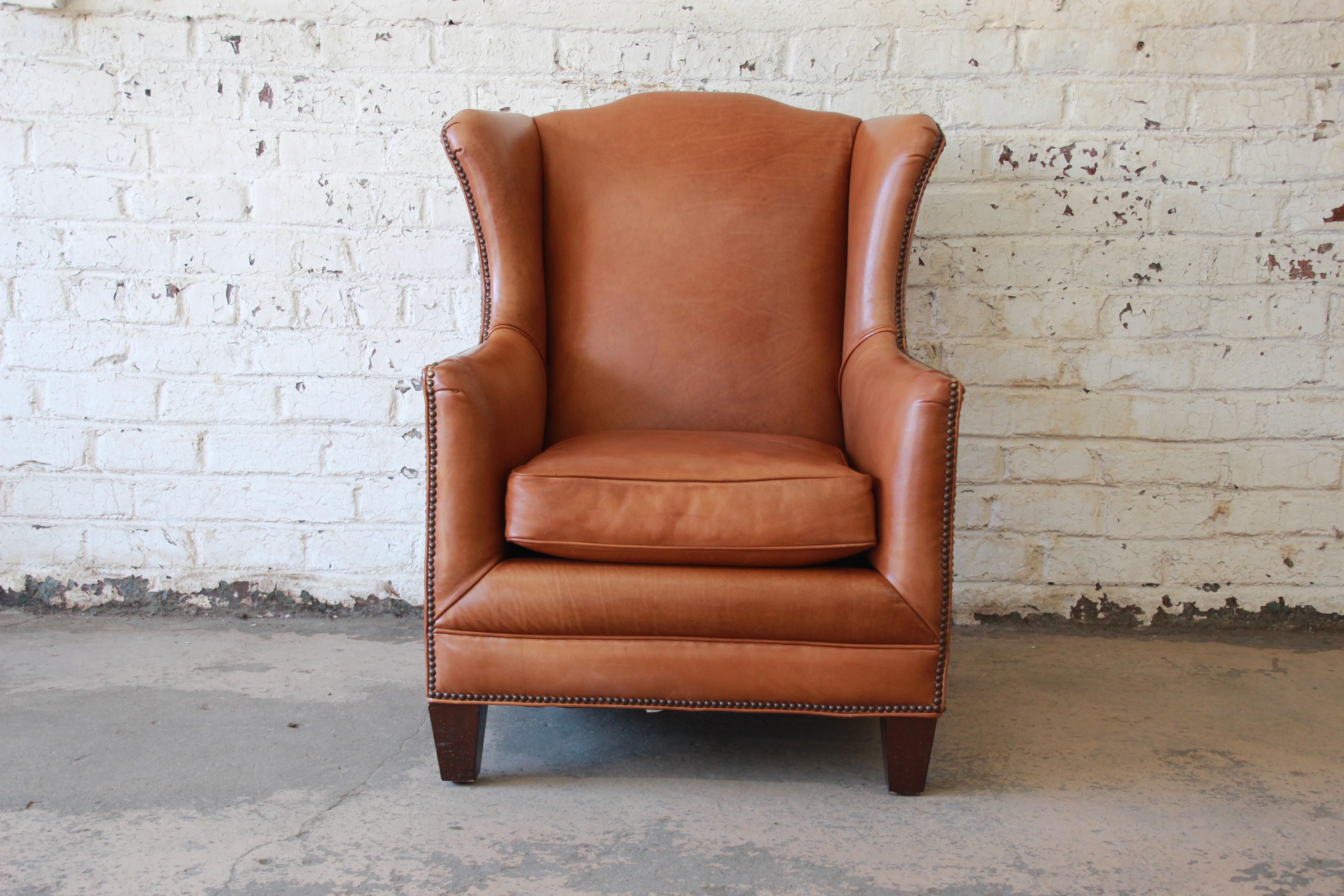 A very nice vintage studded brown leather wingback lounge chair by Henredon. The chair features gorgeous lightly age-worn brown leather. It is extremely comfortable and would fit nicely in both a traditional or modern environment. The chair is in