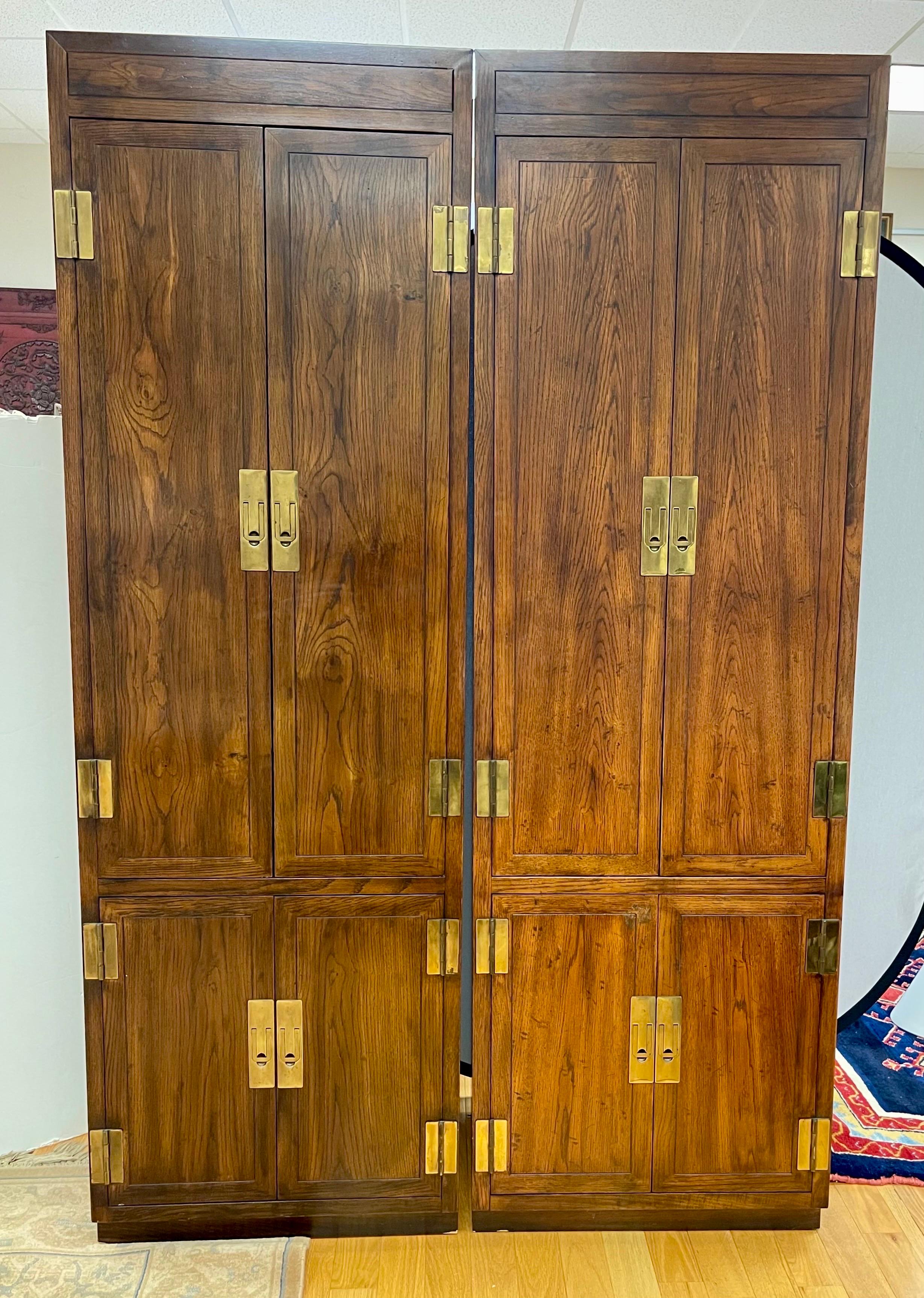 Vintage Campaign style chifforobe cabinets, made by American manufacturer, Henredon. Part of Henredon’s early Scene One collection. Each dark-stained, hardwood case fronts are fitted with brass hinges and flush latch pulls, over a toe-kick base.