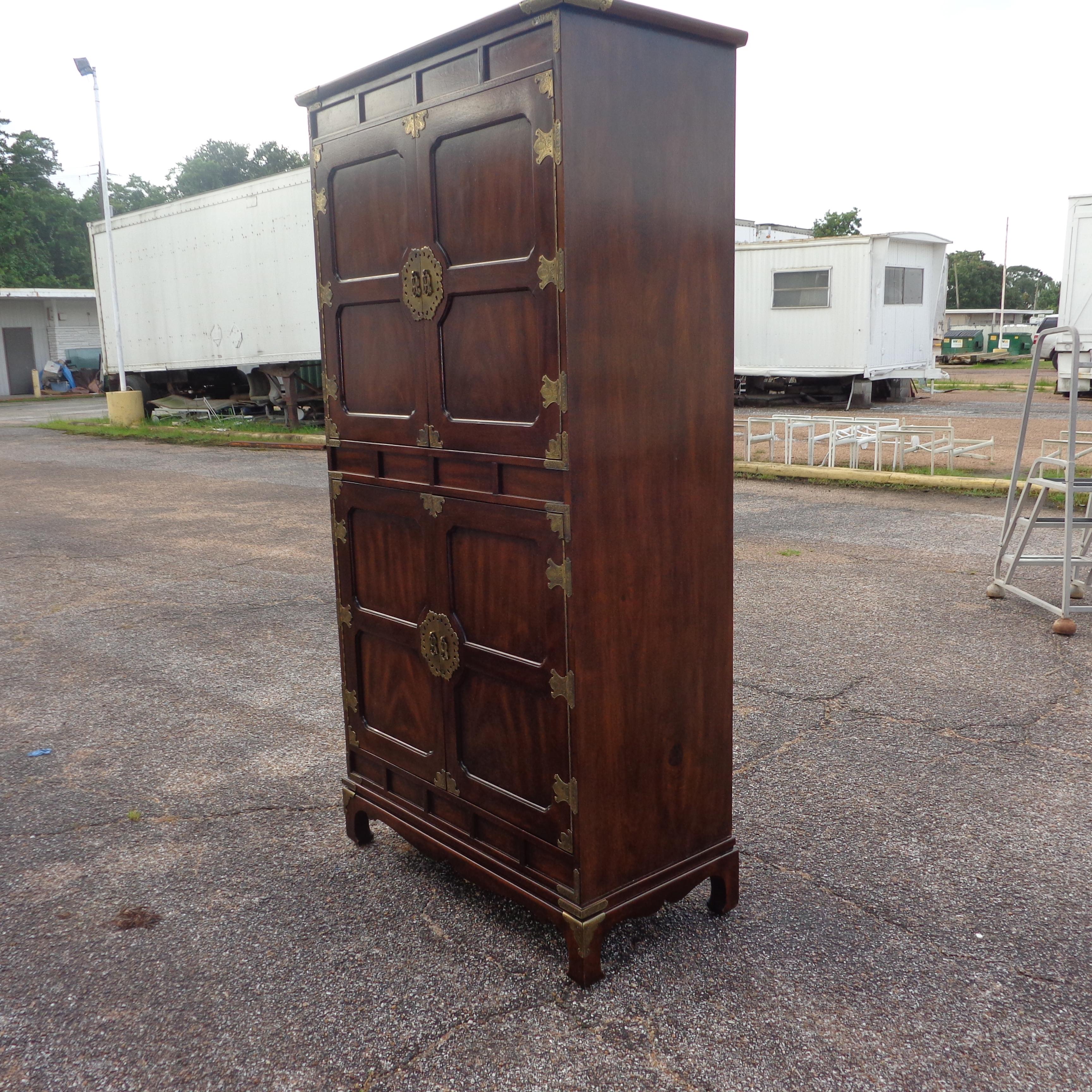 Henredon Tansu Asian campaign dresser 

A tall dresser in the Japanese Tansu campaign style. Made by Henredon circa 1979. 
Features 2 sets of double doors concealing shelving on the top and four drawers on the bottom of the piece. Walnut with