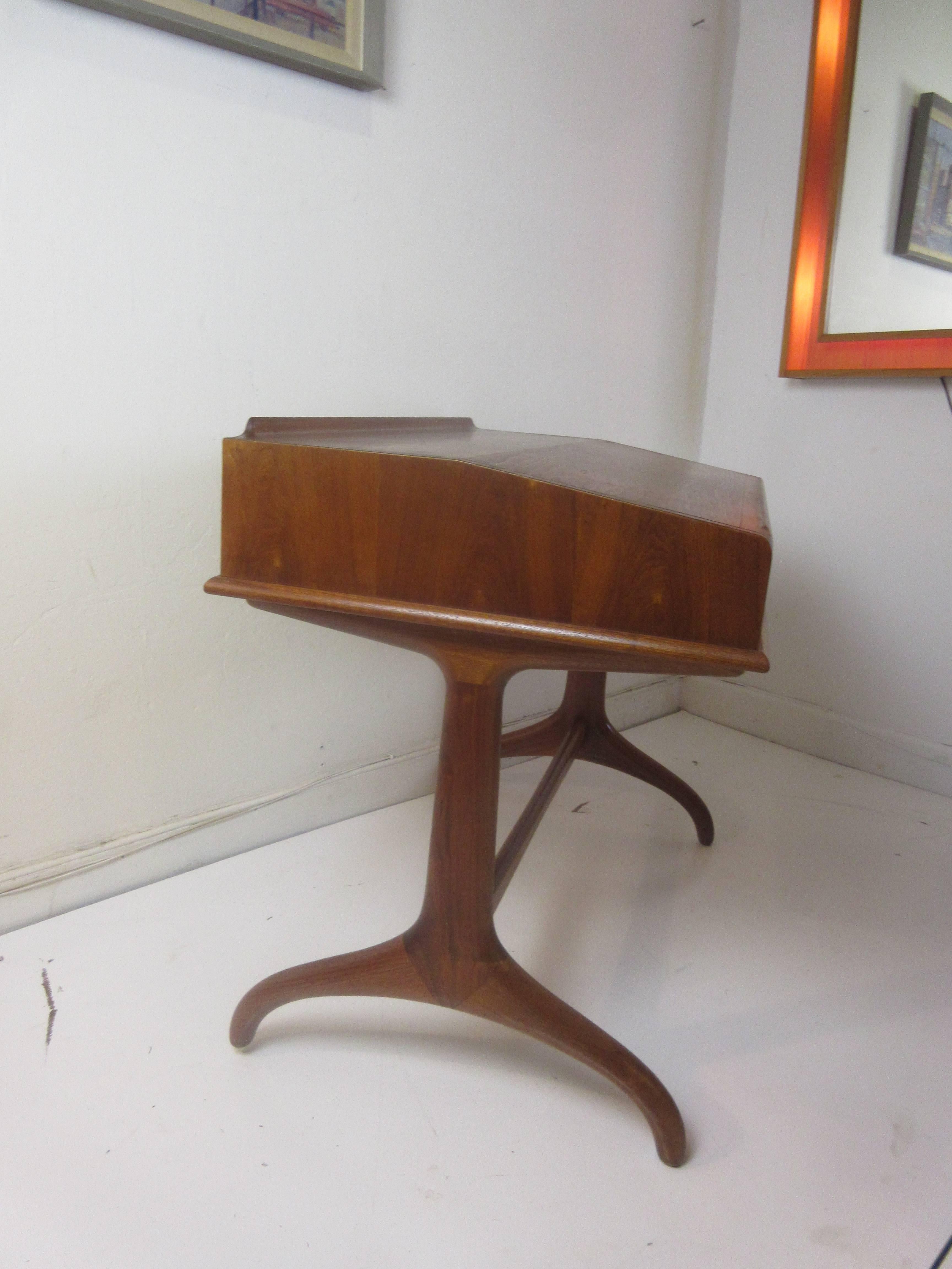 Henredon teak writing desk from the 1960s. Perfect for a computer monitor on the level top and the slanted writing surface has a lip to secure your keyboard and it will be tilted toward you. Graceful bowed legs are joined by a curved tendon. A large