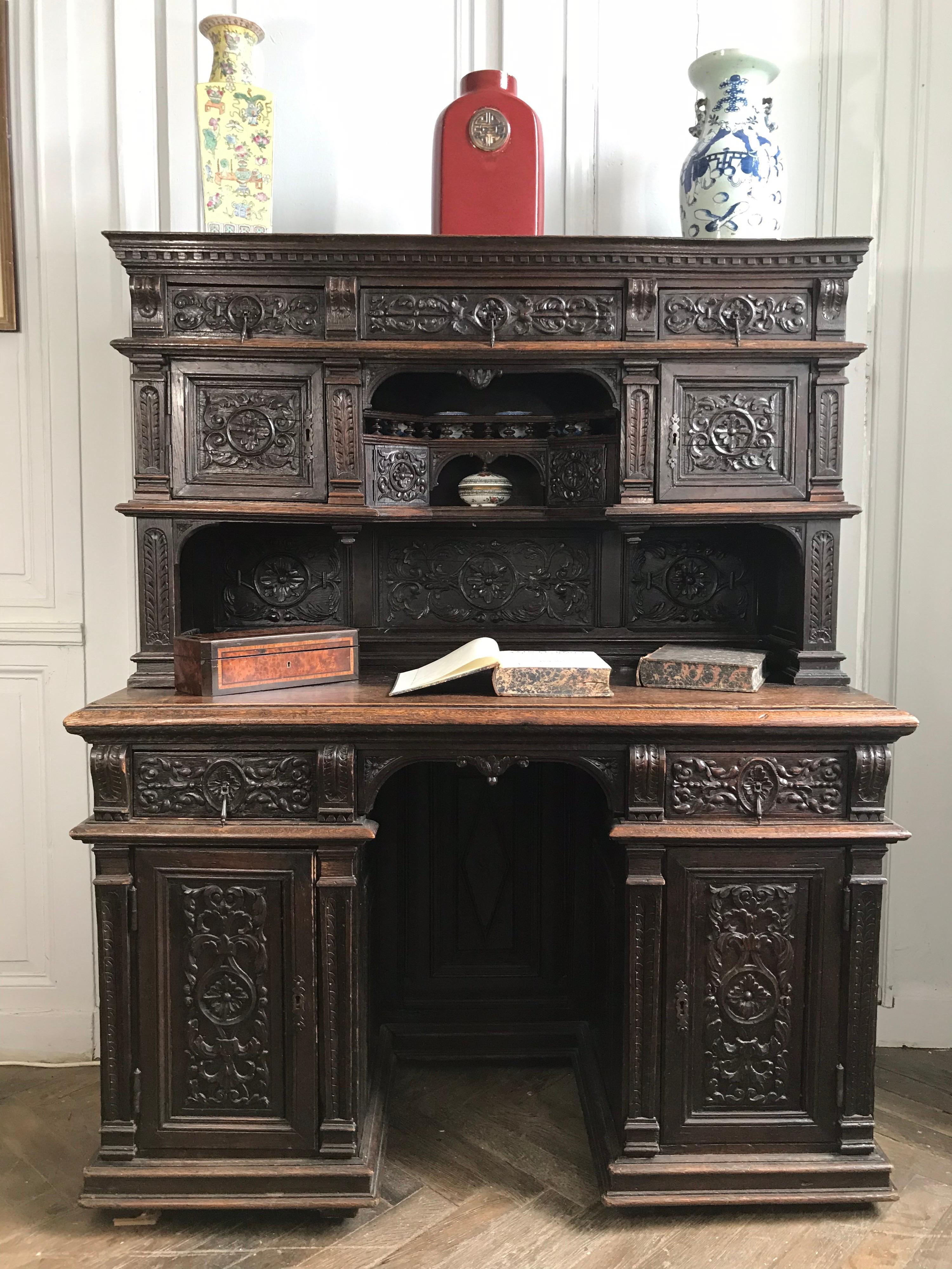 Rare cabinet desk Henri II style in carved oak. The base is made up of two boxes each with a drawer and a door carved and framed by columns. On the wooden top rests the cabinet treated in the manner of a buffet top, with a central niche where a