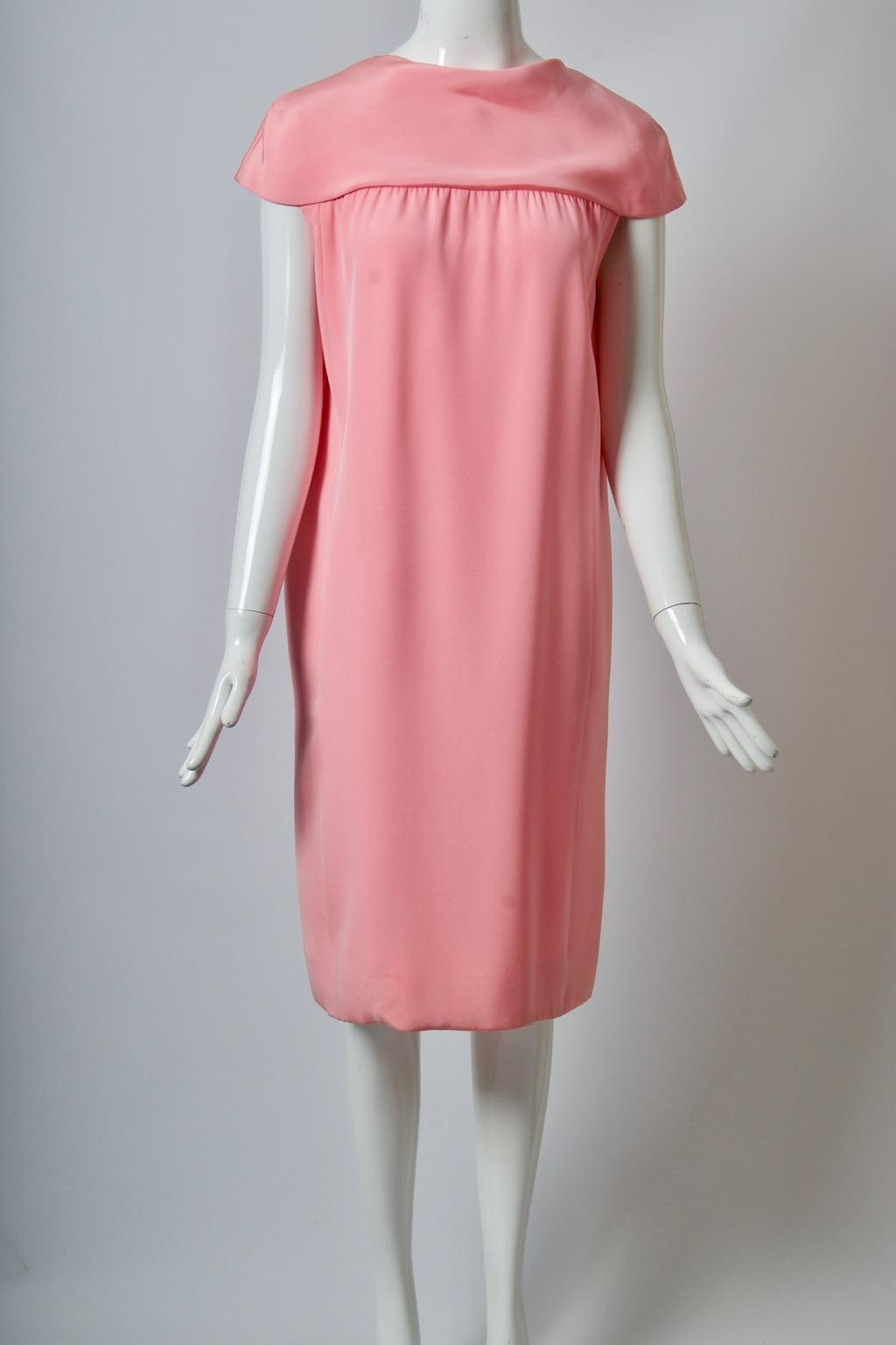 1960s medium-weight silk shift dress in a beautiful shade of pink. The construction features a yoke at top that extends over the shoulders to form cap sleeves. The simple straight shape below has slight gathers under the yoke, hidden pockets in the