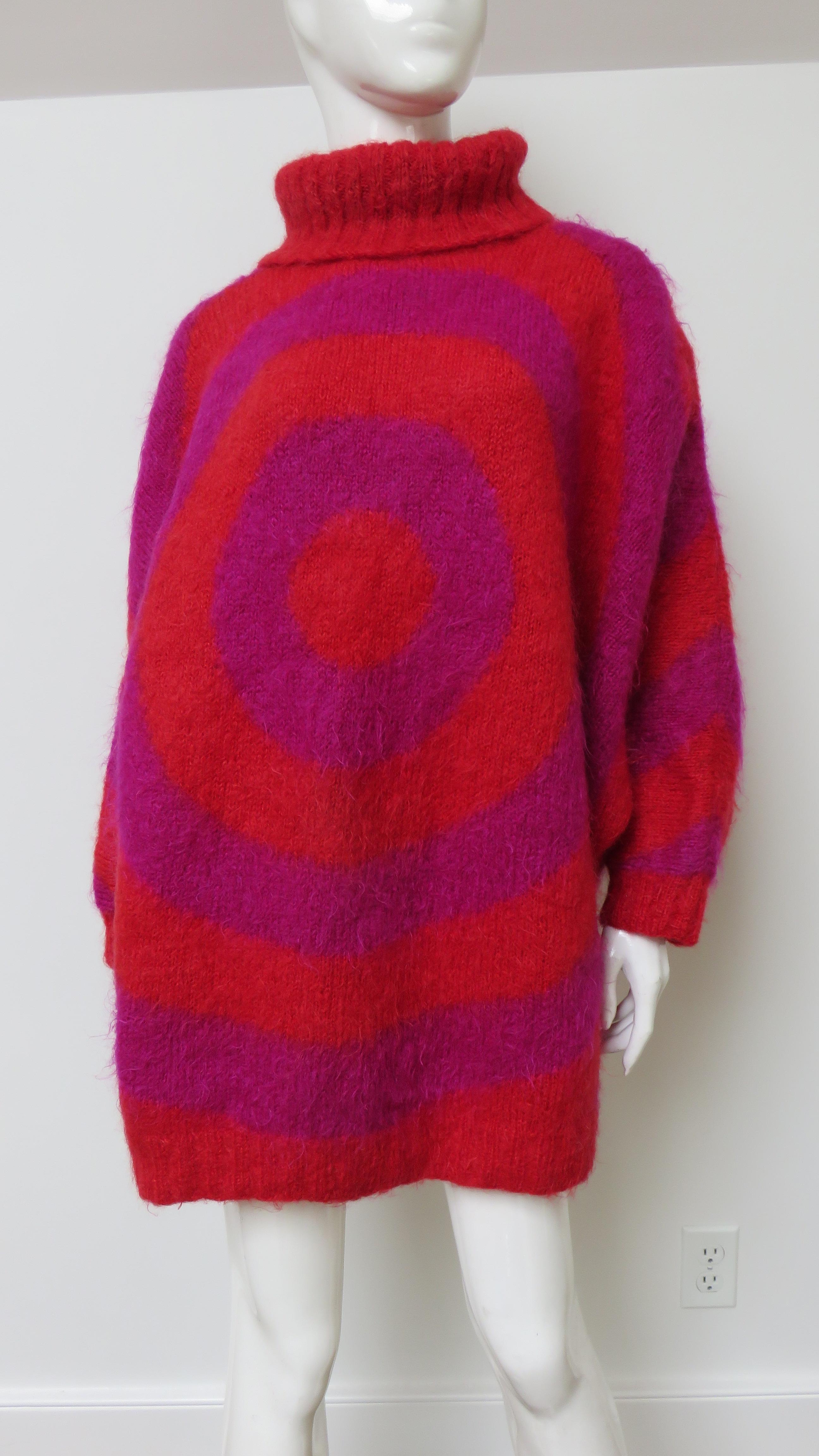Un fabuloso jersey oversize con estampado de círculos rojos y morados.  Tiene cuello alto de 8
