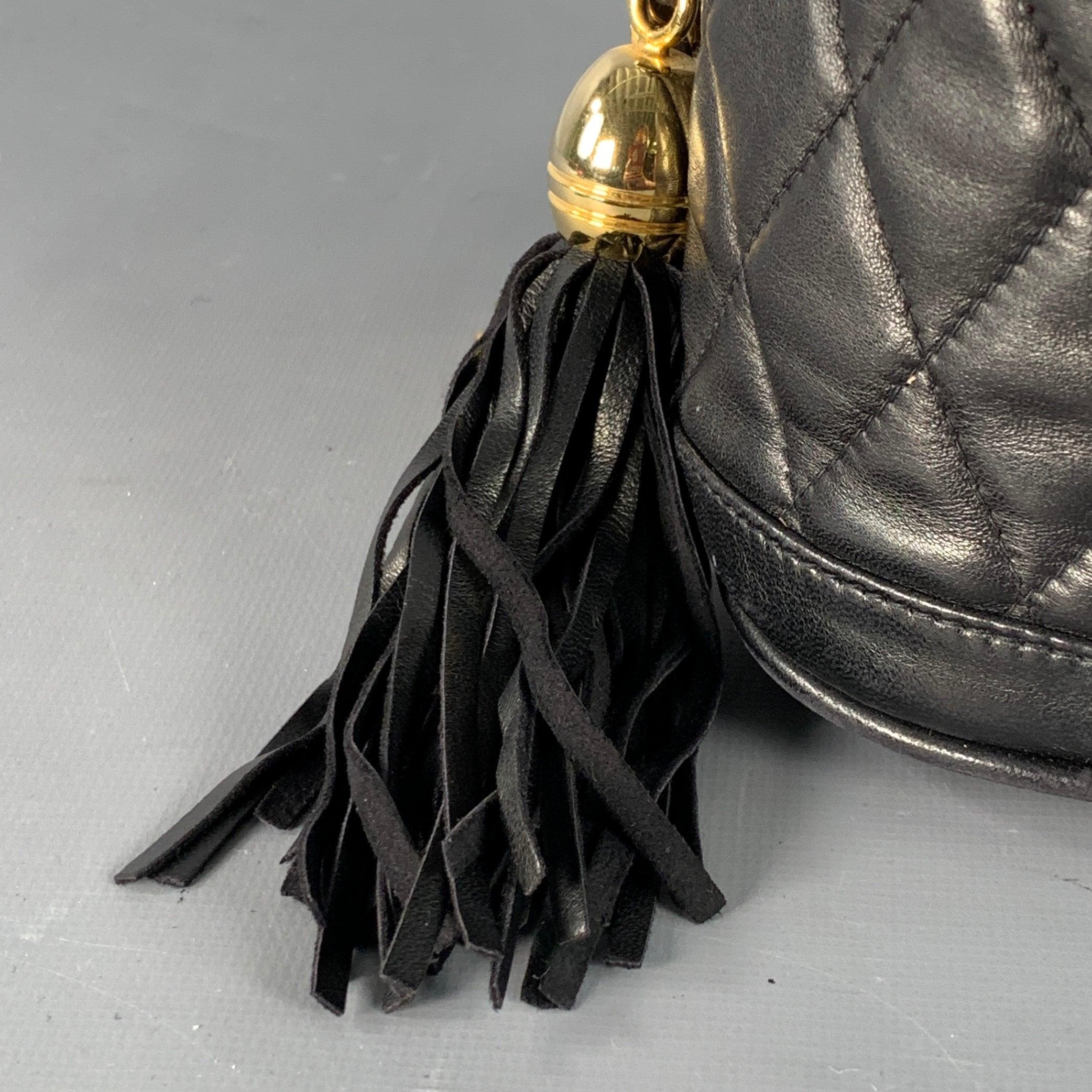 Sac seau Vintage HENRY BENDEL
en cuir noir, avec un style matelassé, une bandoulière à maillons en métal doré, des détails en cuir tressé et un cordon de serrage avec houppes.Très bon état d'occasion. Signes d'usure compatibles avec l'état