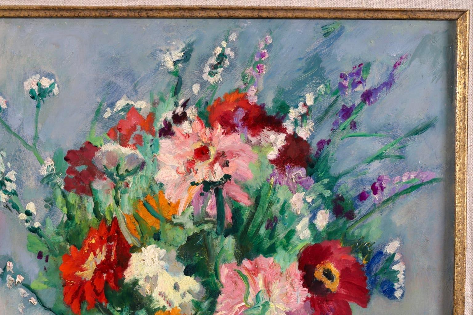 A stunning oil on canvas by French fauvist painter Henri Charles Manguin. The work is a still life of a glass vase of colourful flowers - including zinnias and ranunculus - in red, orange, pink, purple and white. The vase is placed on a table with a