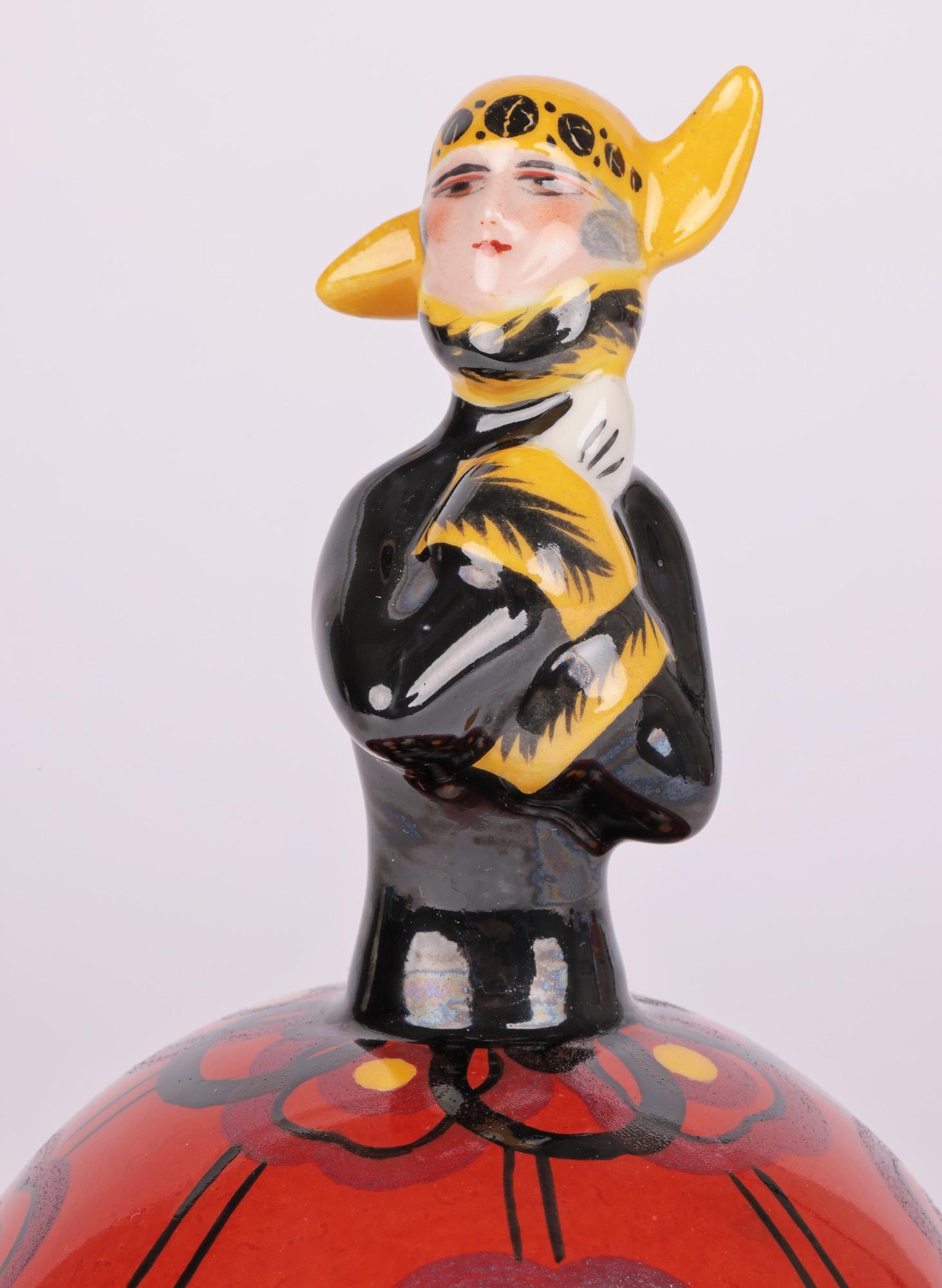 Escasa bombonera de porcelana francesa art déco con tapa en forma de chica flapper de hacia 1930. La bombonera es de forma redonda, se apoya en un pie sin esmaltar y tiene una tapa abovedada con el asa de la tapa formada como el cuerpo de la flapper
