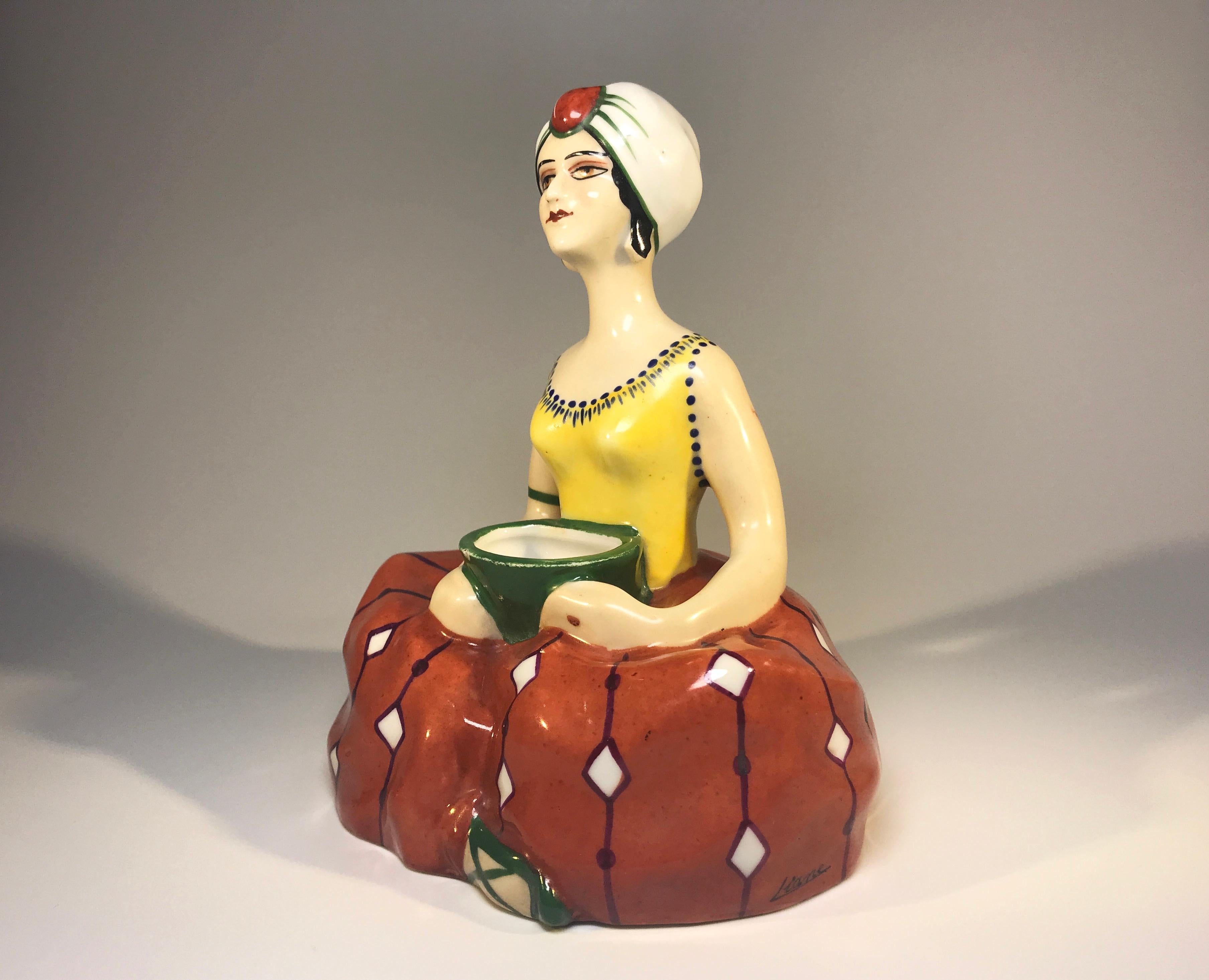 Art Deco enigmatic figural ceramic inkwell by Henri Delcourt of Boulogne-sur-Mer, France
Dressed in dark tangerine and yellow, this turban wearing lady has an air of exotica to her
Undoubtedly Henri Delcourt was one of the greatest names of Art
