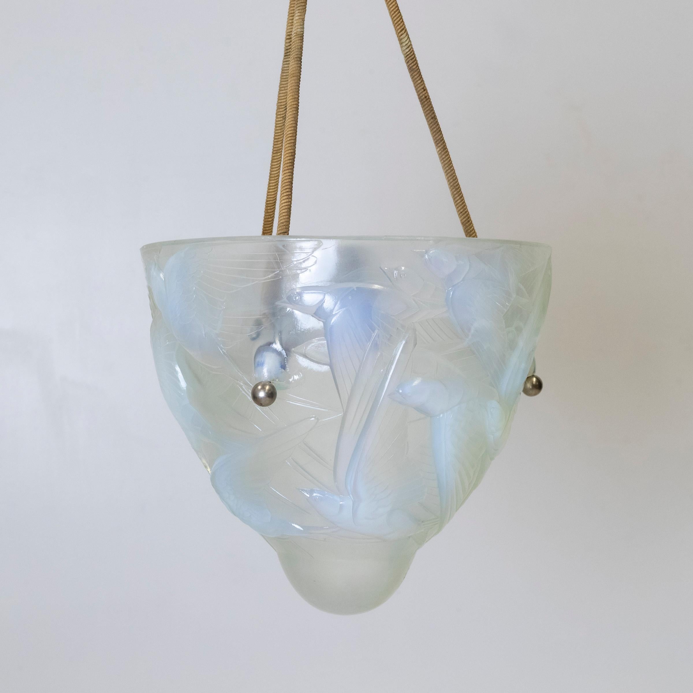 A rare find, this antique Henri Dieupart light suspends from three supports and delivers light through an opalescent moulded glass with abstract bird motifs.

When light hits the glass, the unique inclusions deliver ever-changing, enigmatic hues