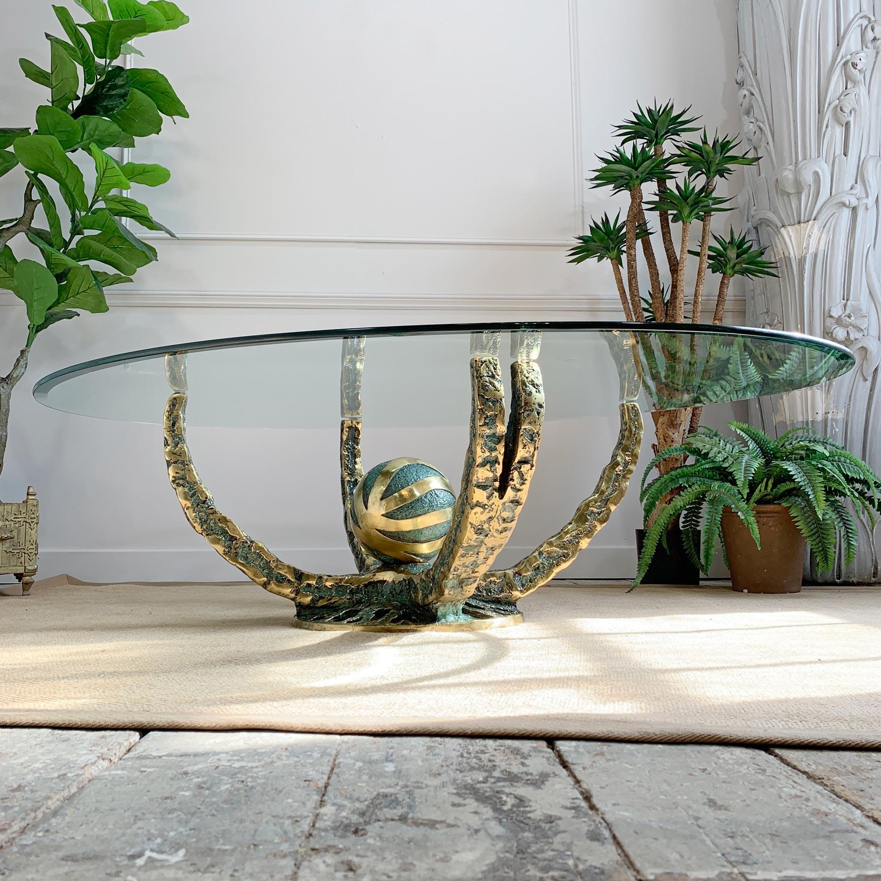 Table centrale ou table basse 'Octo' en bronze brutaliste de Fernandez. Cette étonnante table artisanale en bronze brut et doré date du début des années 1970 et est accompagnée de son grand plateau de verre ovale d'origine à bord biseauté. Fabriqué