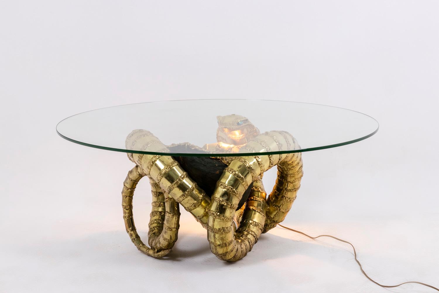 Henri Fernandez, by.

Coffee table “Cobra”, depicting a snake and presenting an amethyst in its center with a lighting system placed under its neck to illuminate the amethyst. Round glass top.