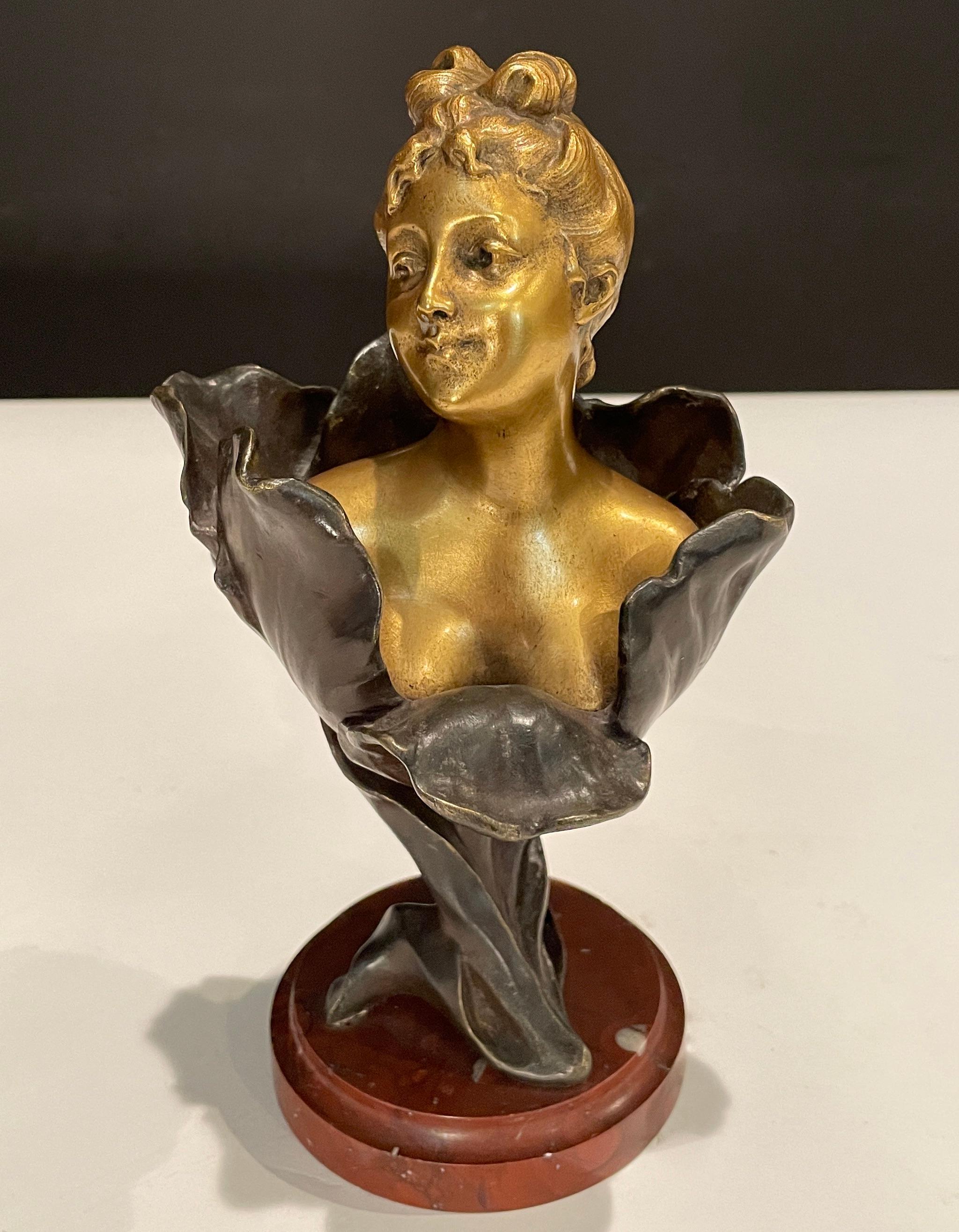 A fine unusual Art Nouveau two tone gilt and patinated bronze bust of a young lady rising from the center of a tulip flower with fine detail, raised on a breche griotte circular marble plinth, signed H Godet & inscribed Med d'Or to represent that